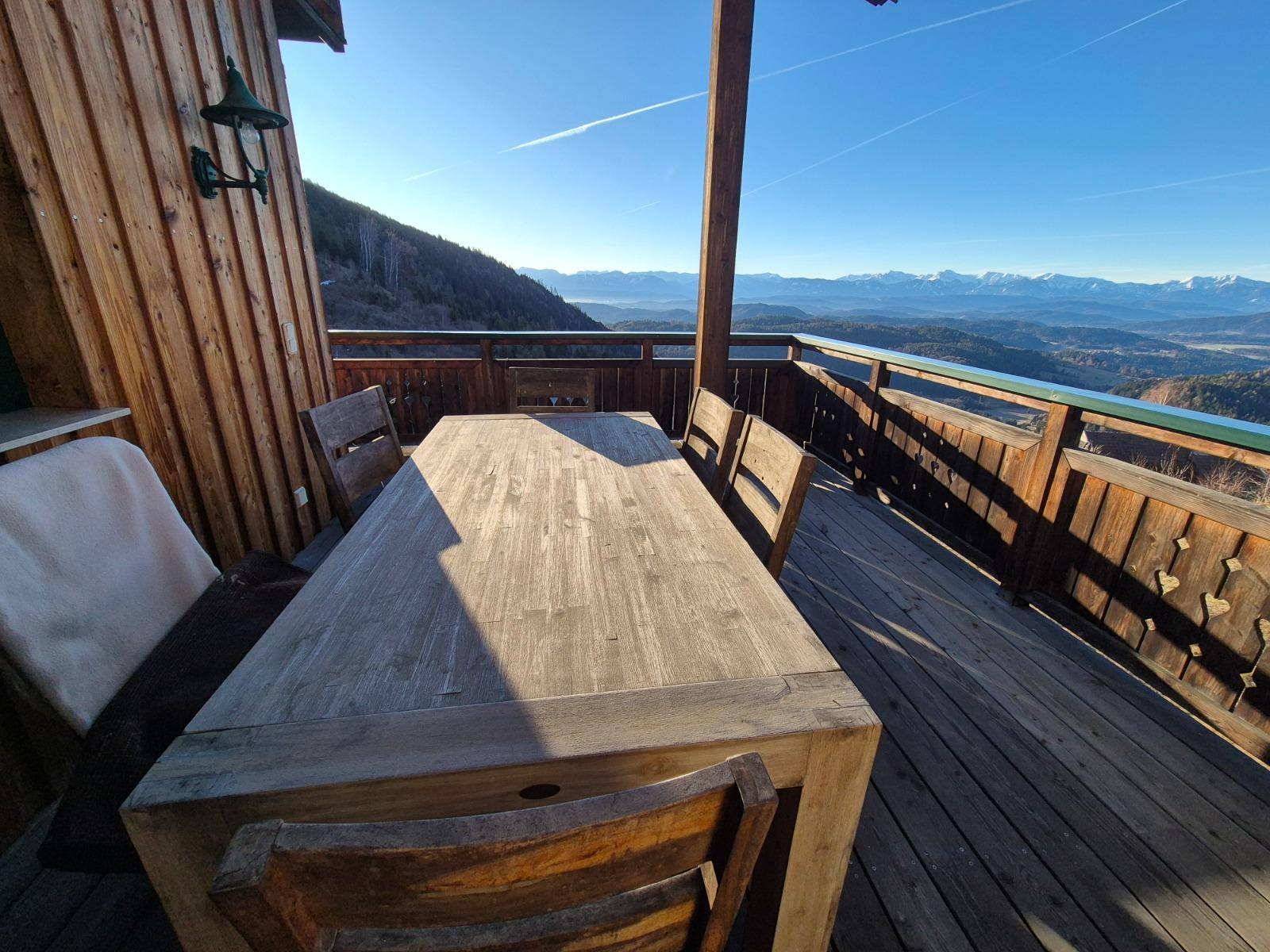 Geräumige Holzterrasse mit Esstisch und atemberaubendem Panoramablick auf die Berge.