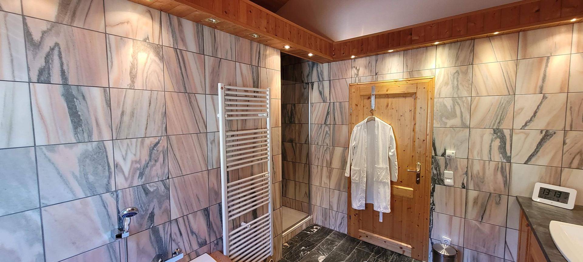 Duschbereich im Badezimmer mit beheiztem Handtuchhalter und stilvollen Fliesen.