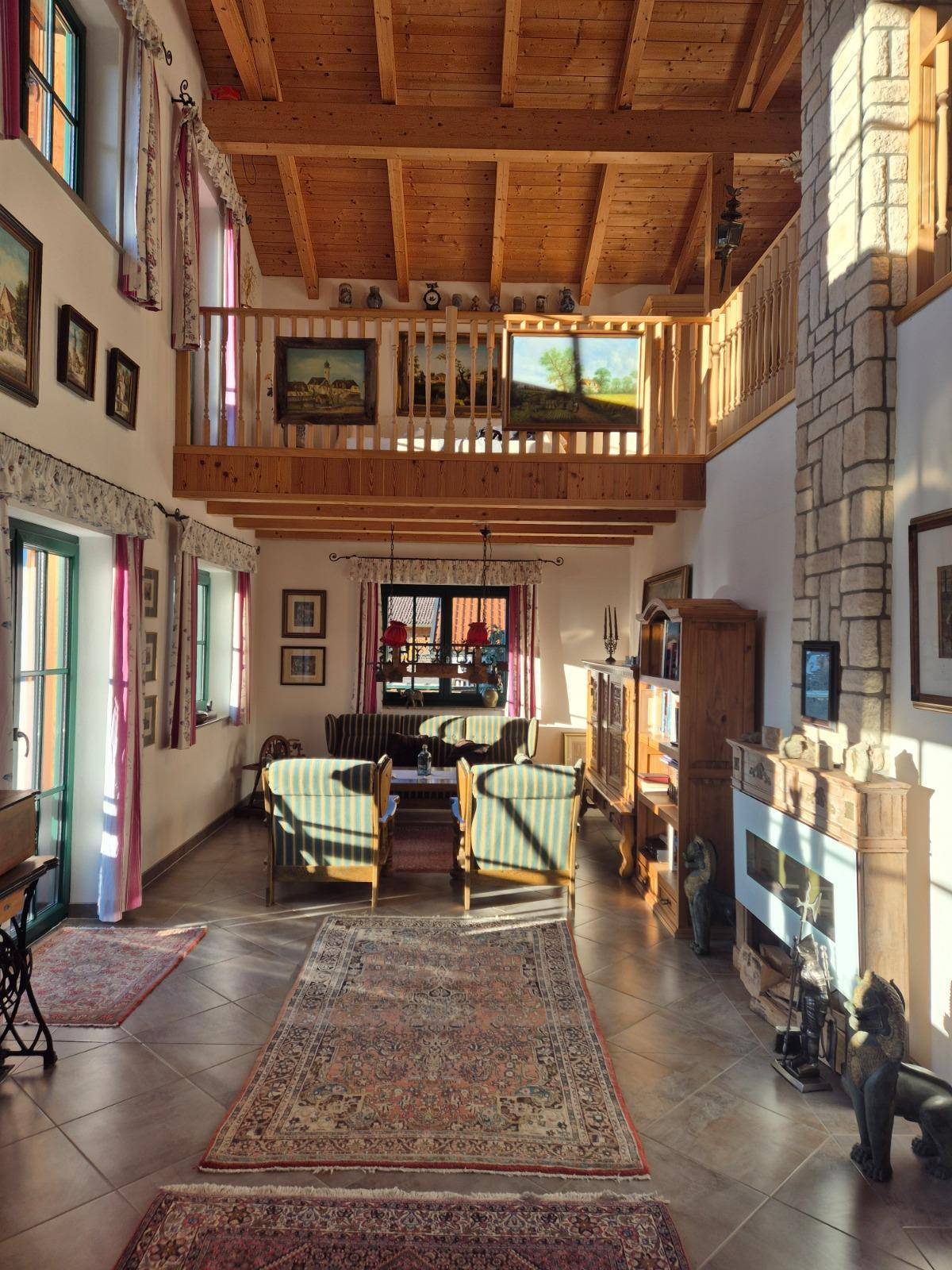 Helles Wohnzimmer mit hohen Holzdecken, Kamin und Galeriebereich.