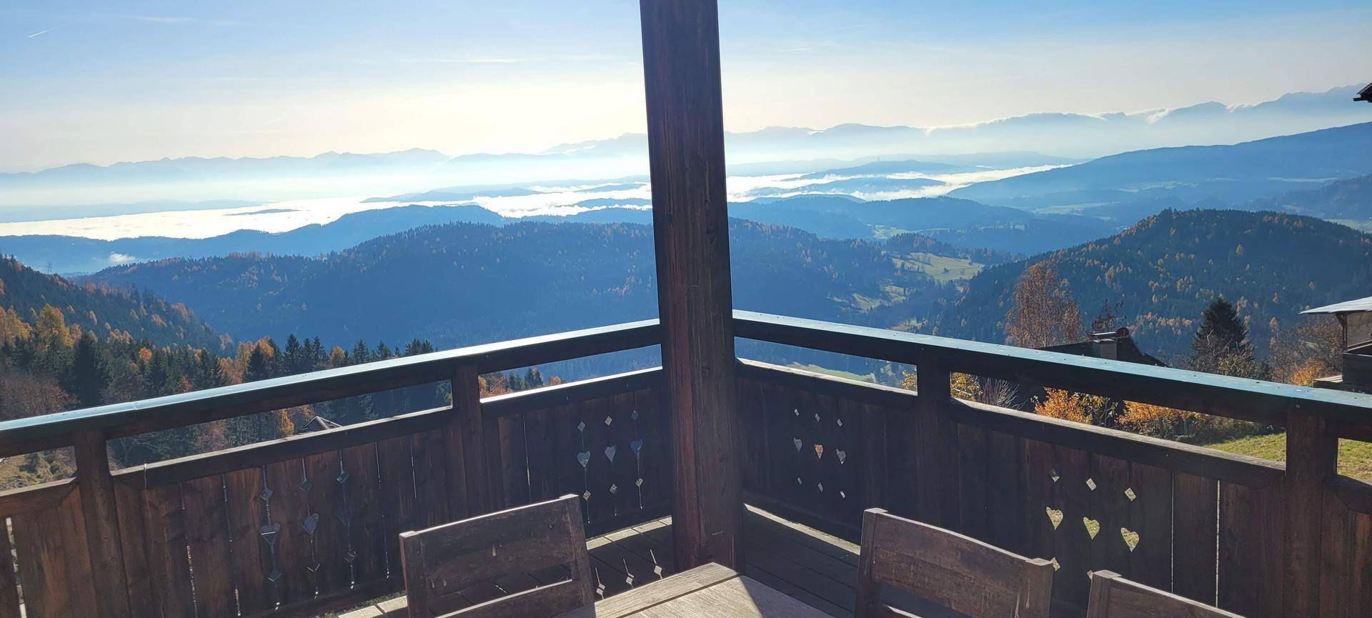 Sonniger Balkon mit Holzgeländer und spektakulärem Weitblick über die Bergwelt.