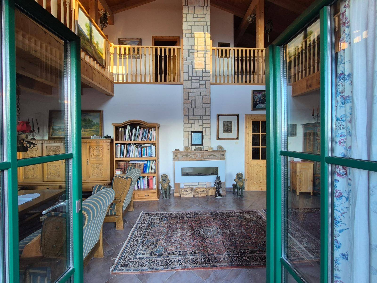 Gemütliches Wohnzimmer mit Kamin, Bücherregal und Zugang zum Außenbereich.
