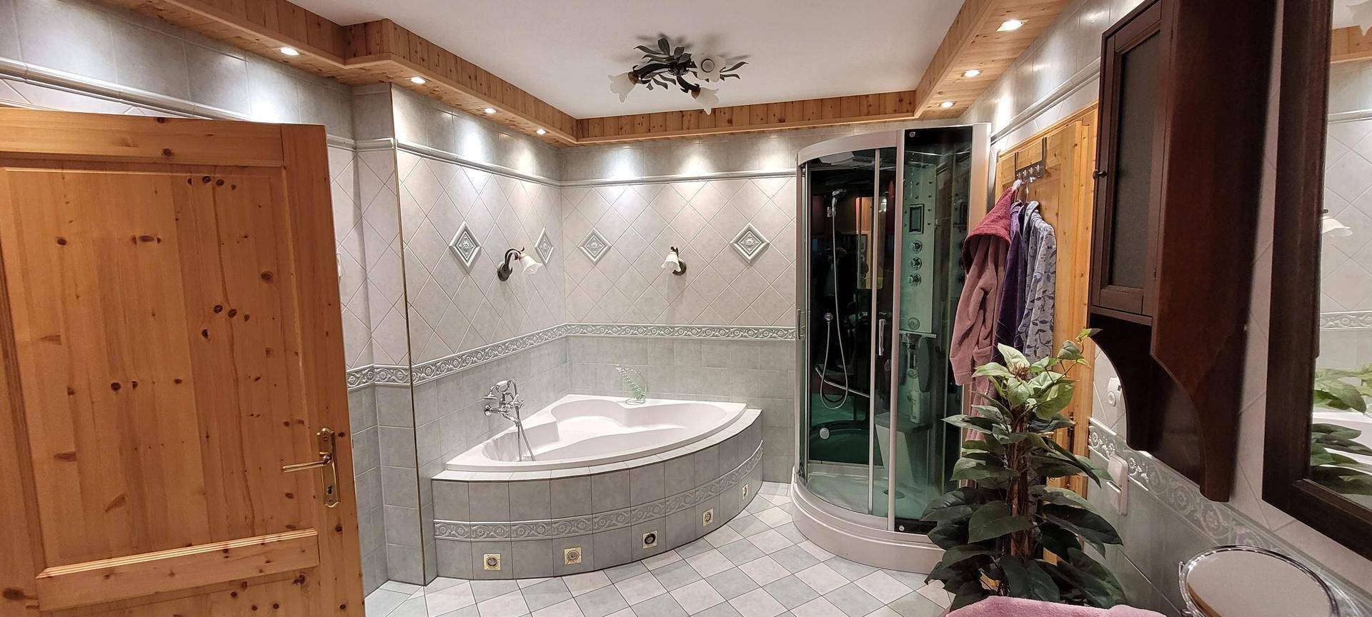 Geräumiges Badezimmer mit Eckbadewanne, Duschkabine und Holzdetails.