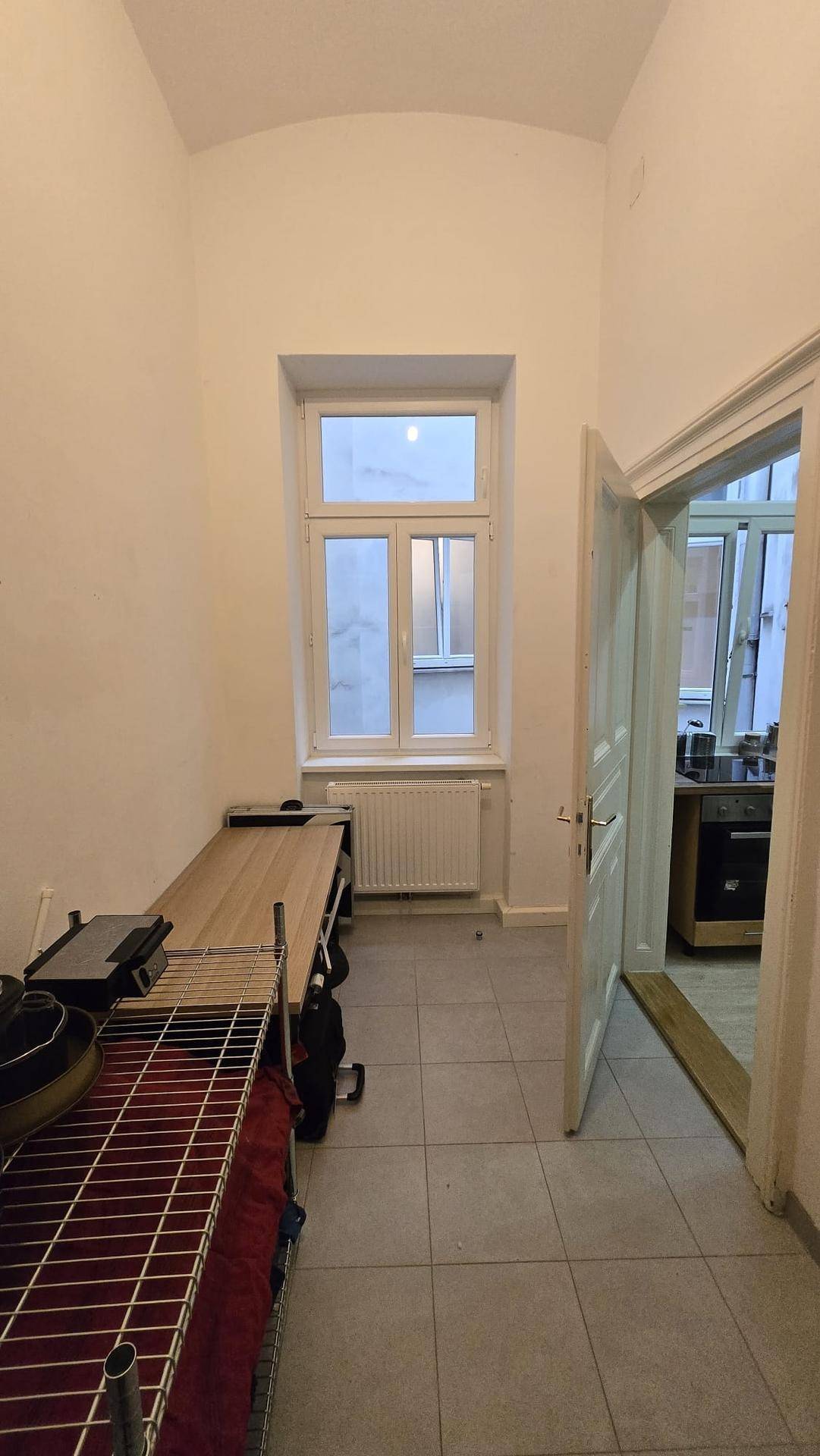 Abstellraum mit Fliesenboden, Fenster und Regalen für Lagerung.