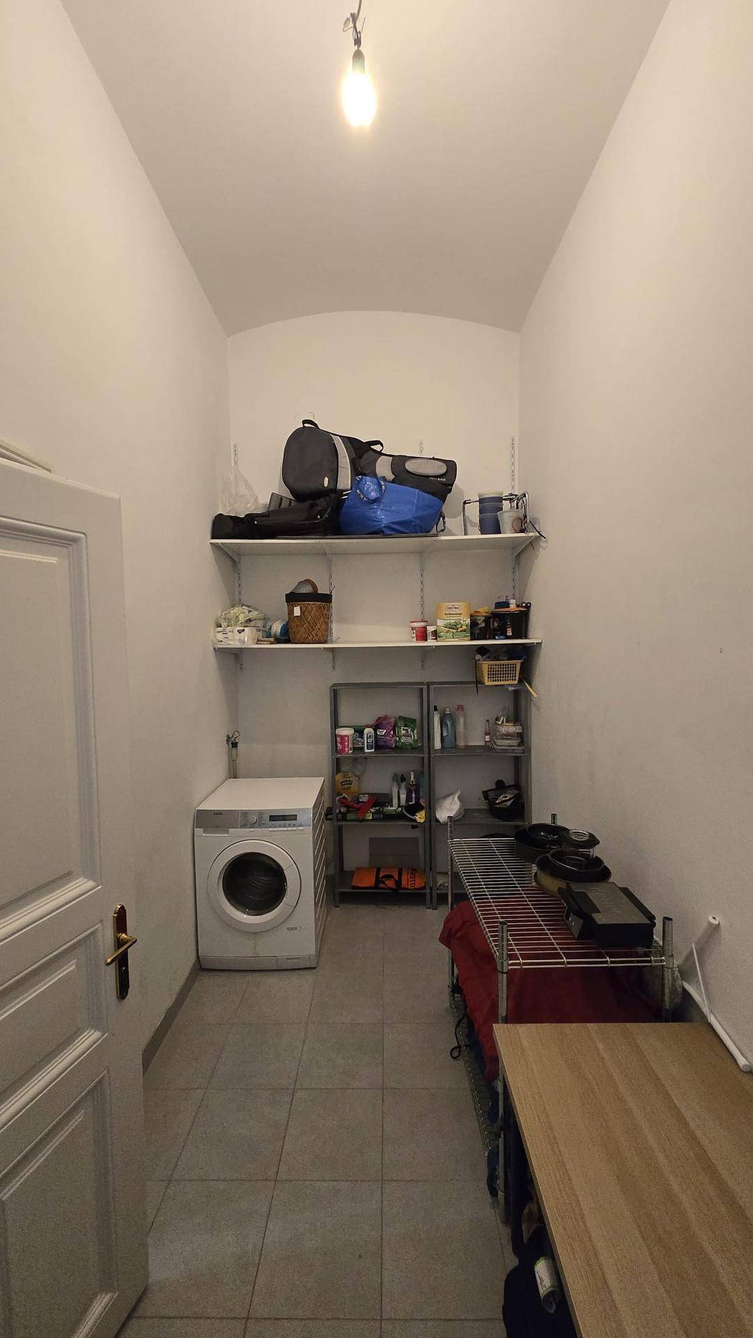 Hauswirtschaftsraum mit Waschmaschine, Regalen und Fliesenboden.