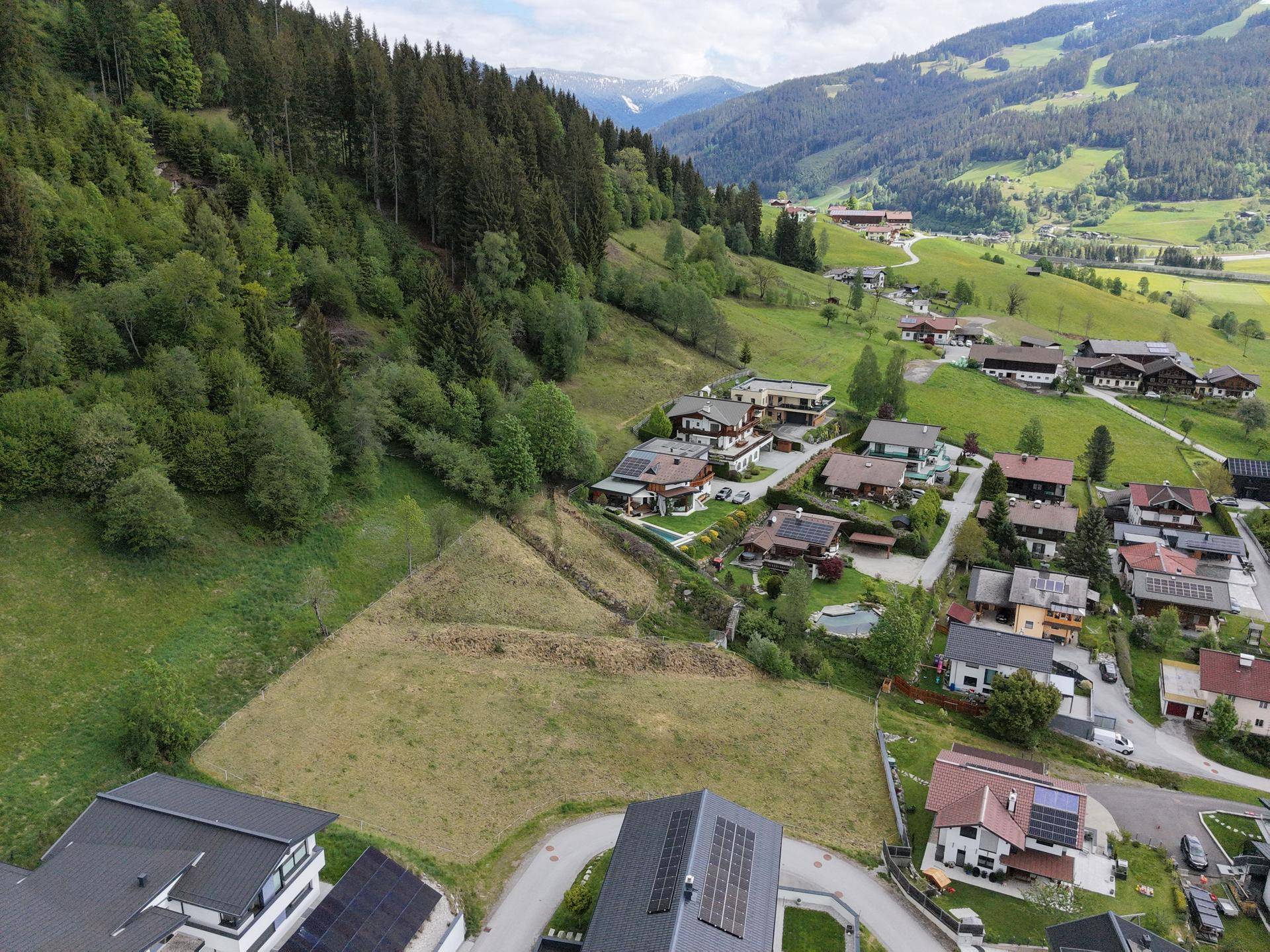 Panoramablick auf Wohnhäuser an einem bewaldeten Hang mit weitem Blick über das Tal.