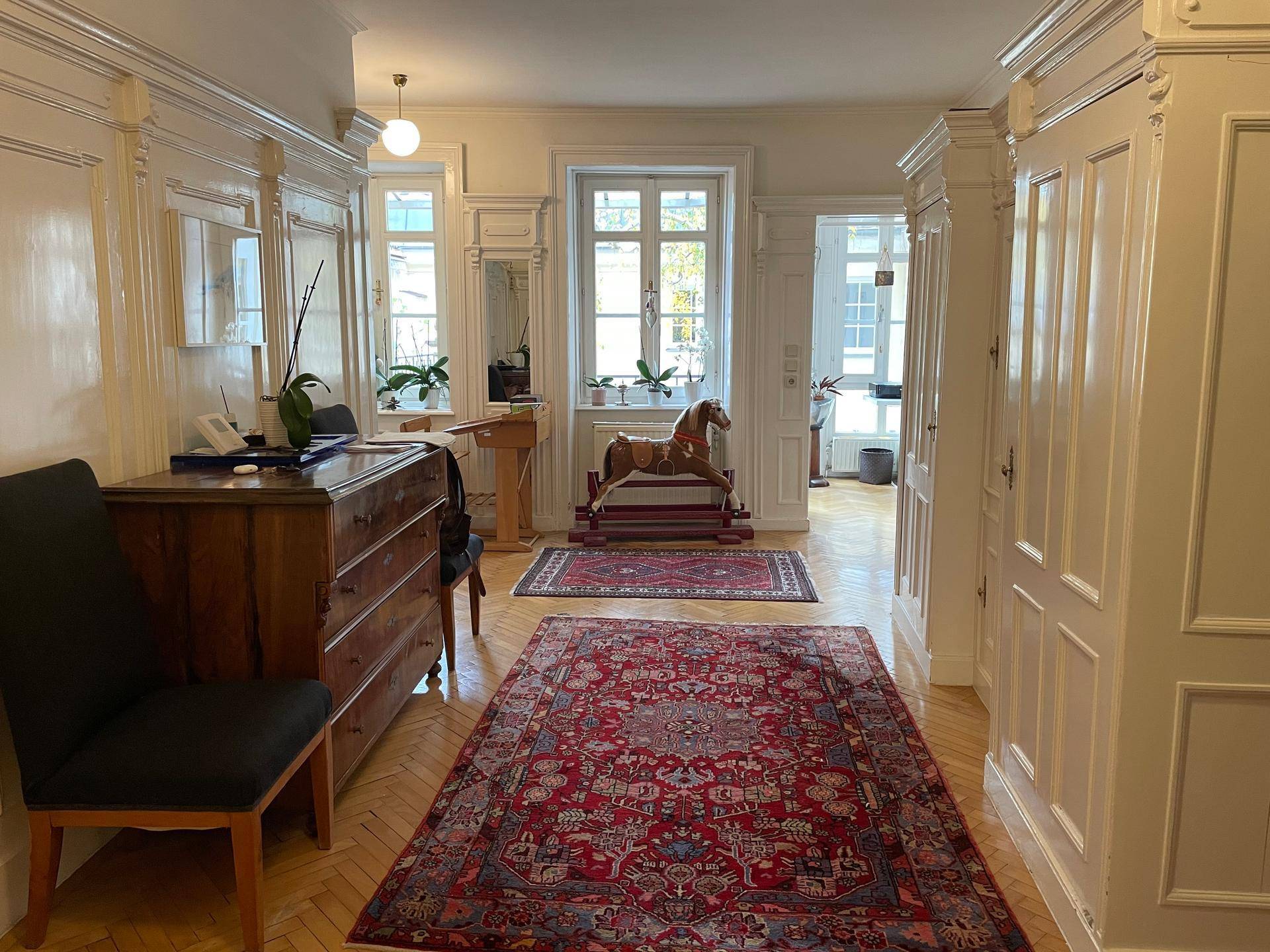 Eleganter Flur mit Fischgrätparkett, hohen Decken und aufwendigen Wandvertäfelungen.