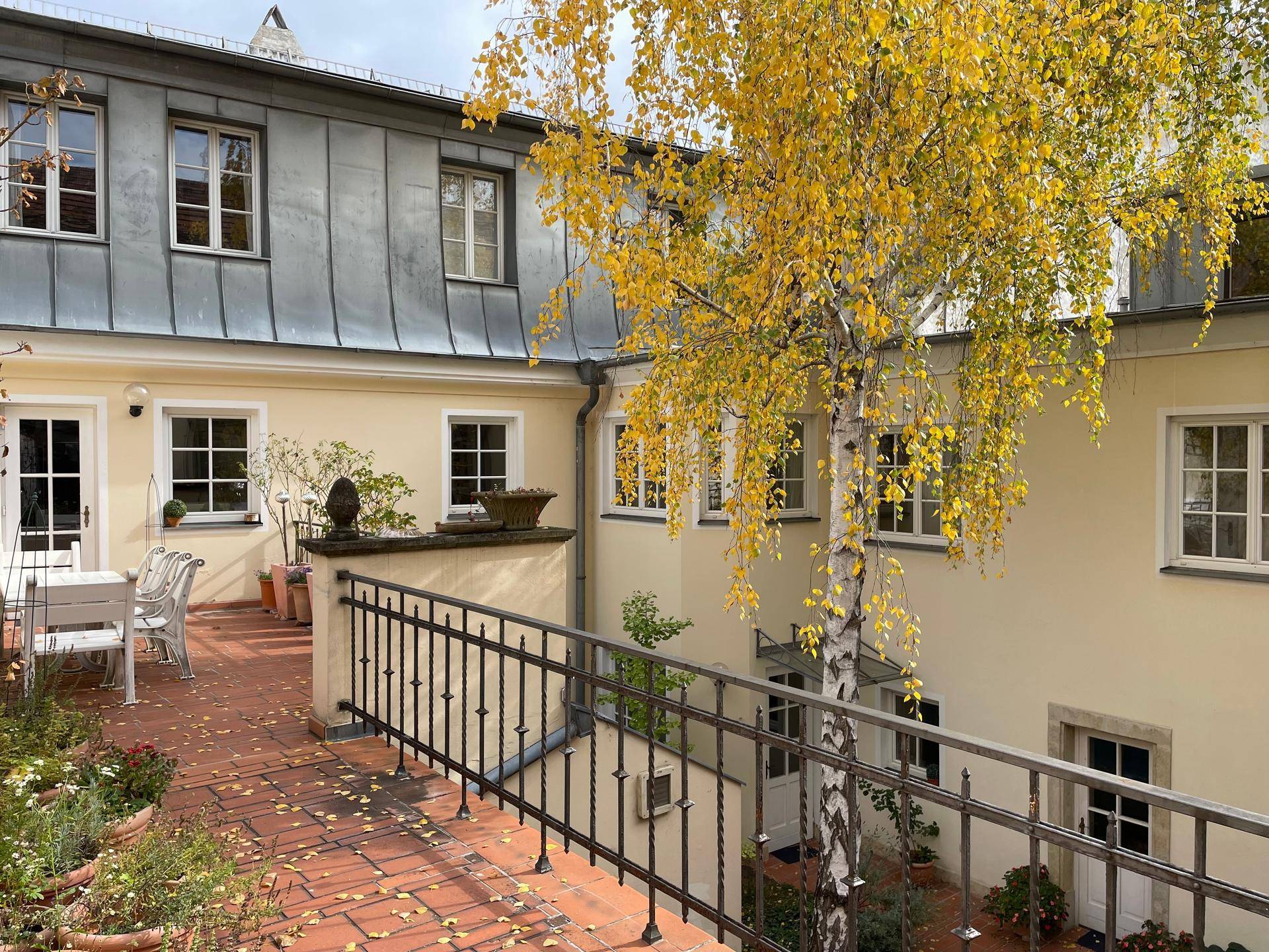 Weitläufige Terrasse mit schmiedeeisernem Geländer und Blick auf den begrünten Innenhof.