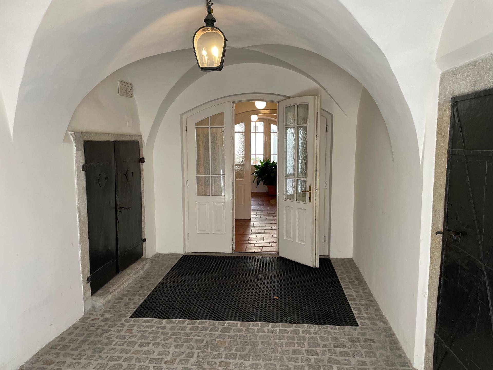 Historischer Eingangsbereich mit Gewölbedecke, Kopfsteinpflaster und Doppeltüren zum Innenhof.