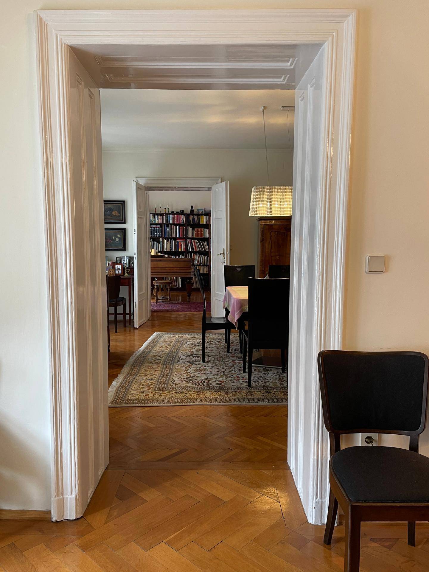 Blick durch eine elegante Türöffnung in ein Esszimmer mit Parkettboden und klassischer Einrichtung.