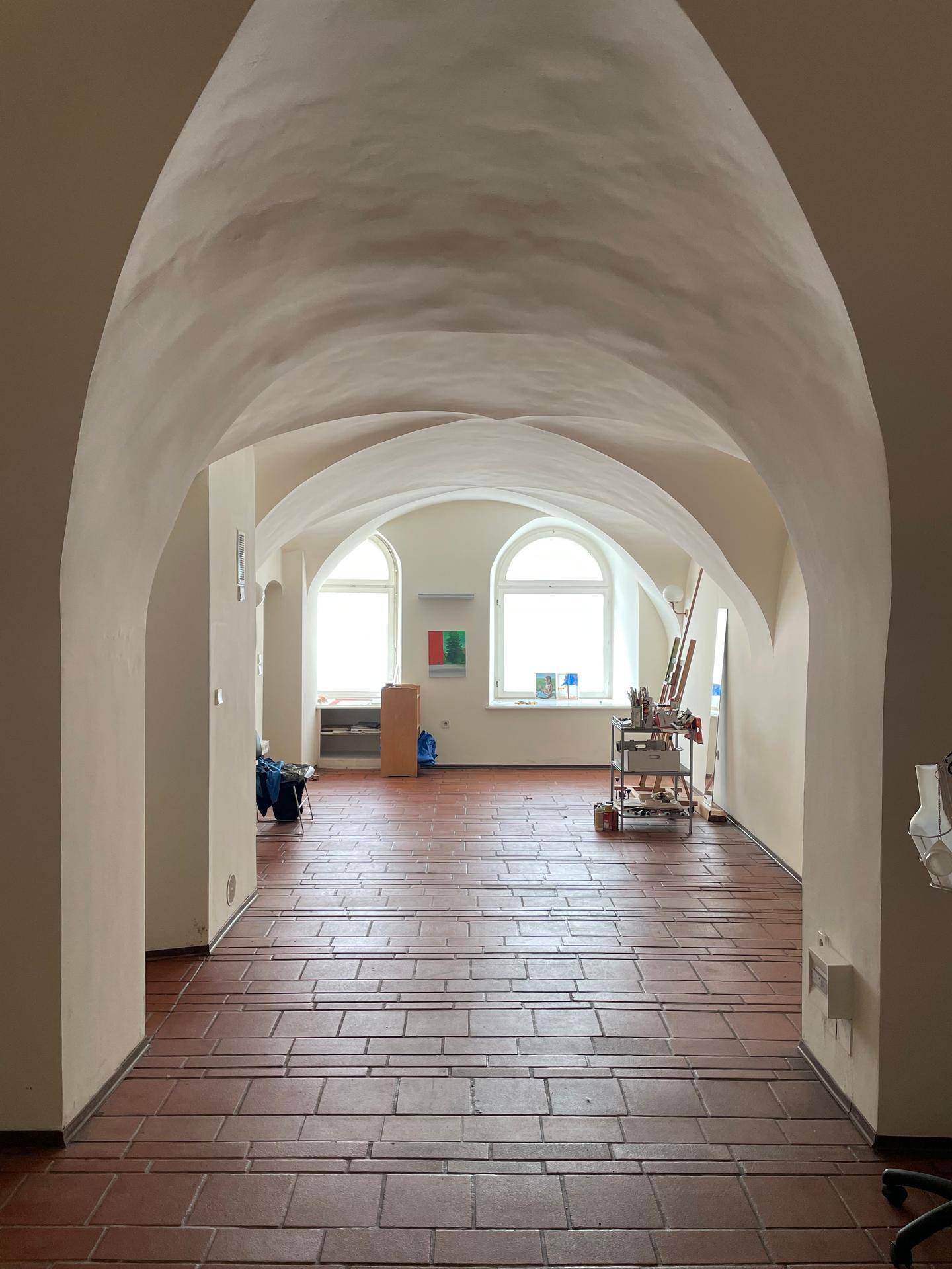 Großer, heller Raum mit beeindruckenden Gewölbebögen und Terrakottaboden, ideal für ein Atelier.