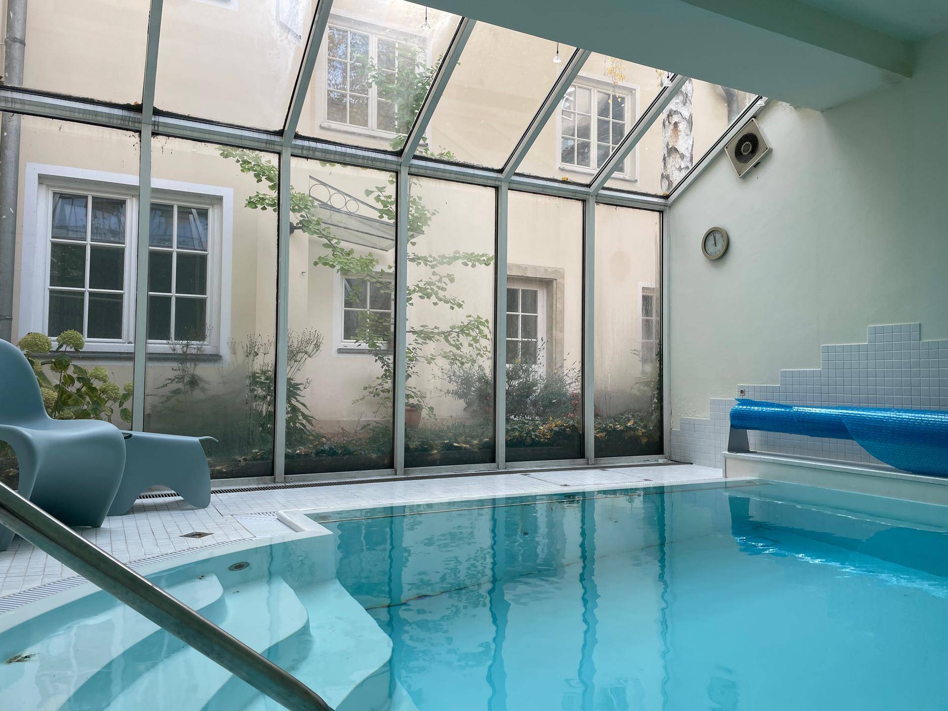 Innenpoolbereich mit Glasdach und Blick auf den Innenhof, ideal für Wellness und Sport.