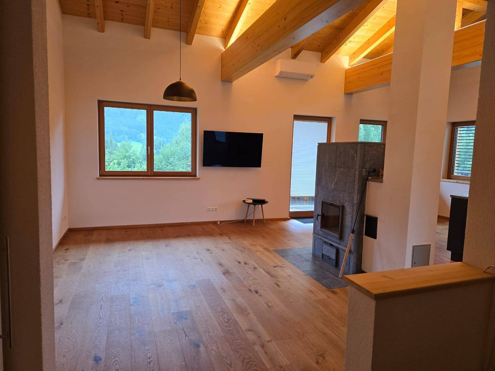 Geräumiges Wohnzimmer mit Holzbalkendecke, Eichenparkett und modernem Kaminofen.