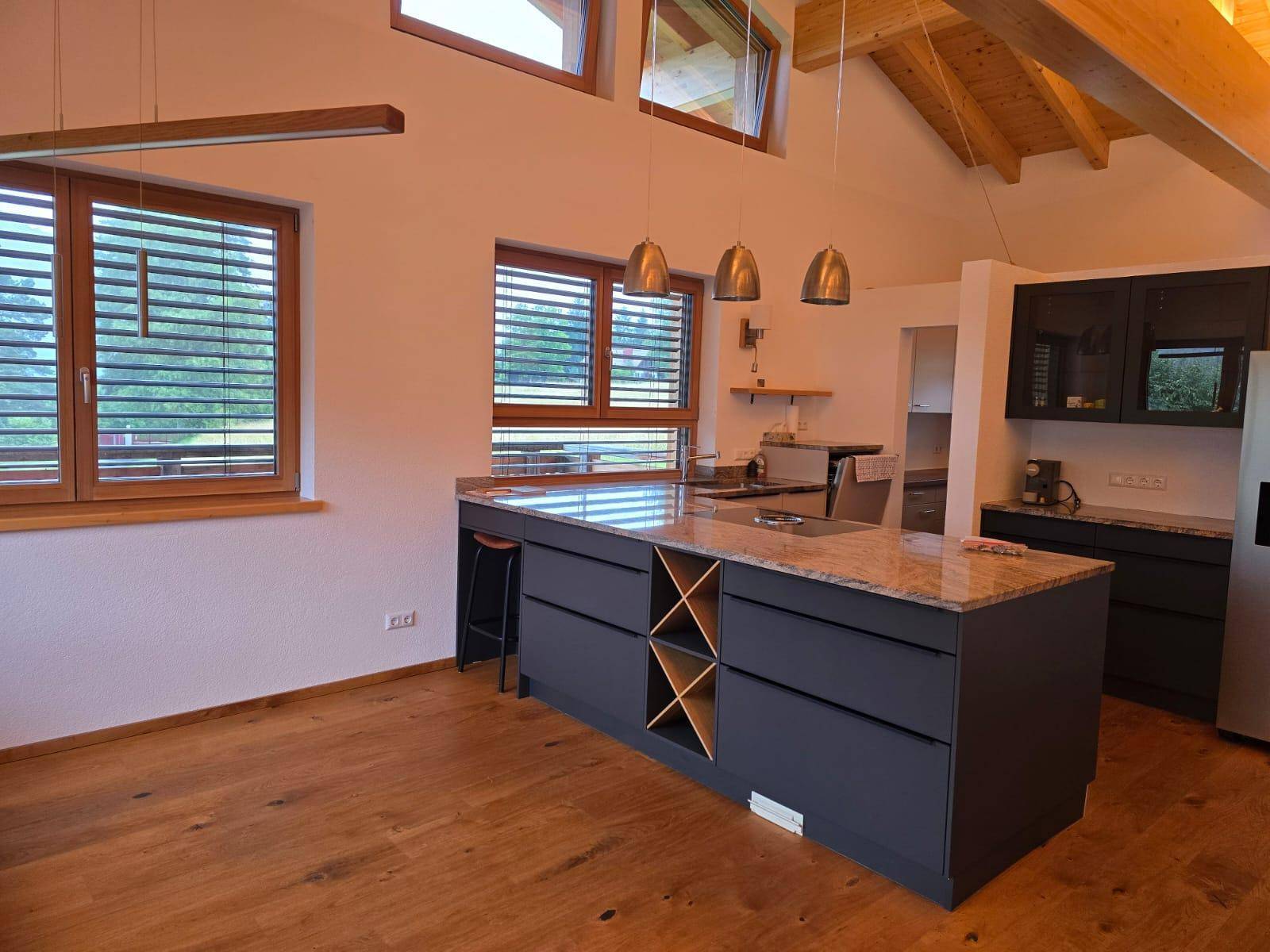 Helle, moderne Küche mit Kücheninsel, Granitarbeitsplatte und viel natürlichem Licht.