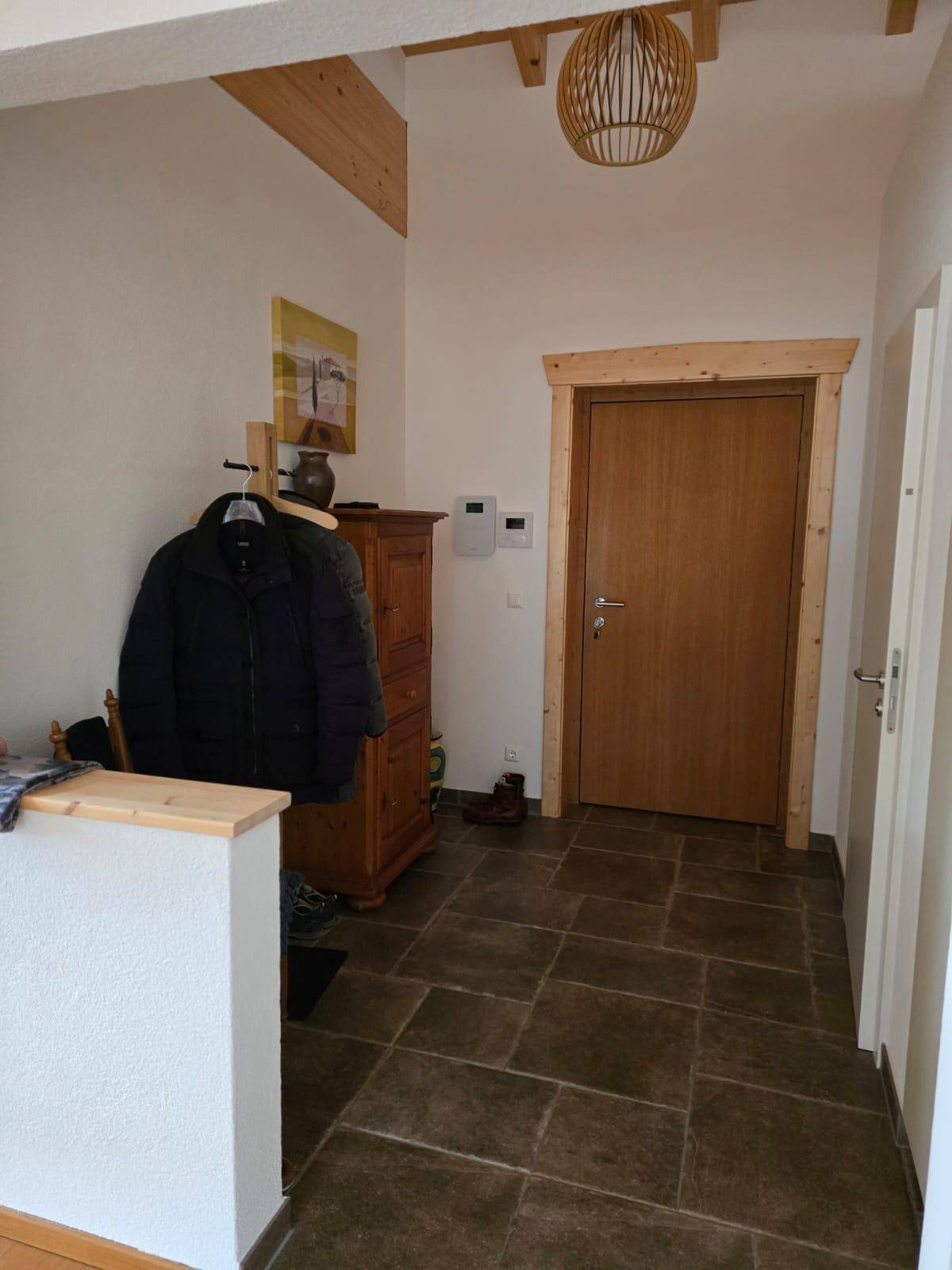 Eingangsbereich mit Fliesenboden, Garderobe und Holztür.