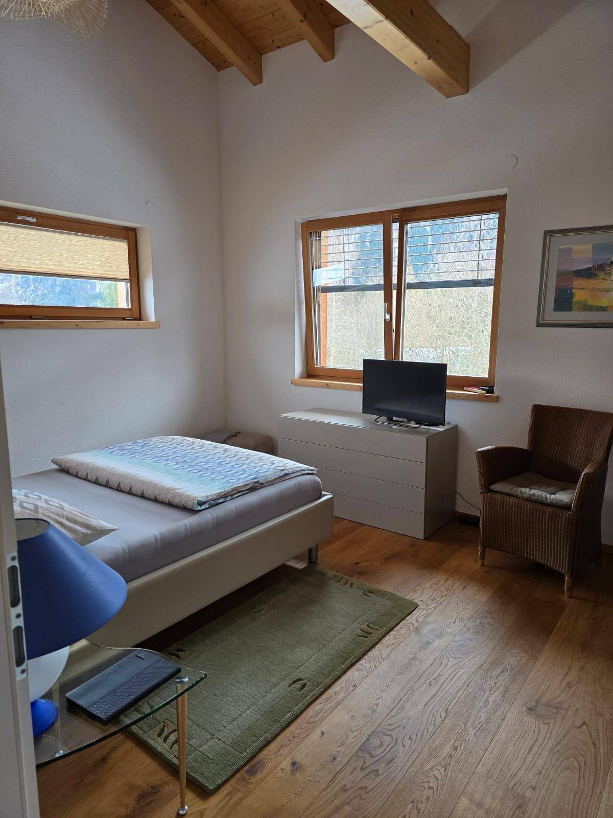 Helles Schlafzimmer mit Holzbalkendecke, Eichenparkett und Blick ins Grüne.