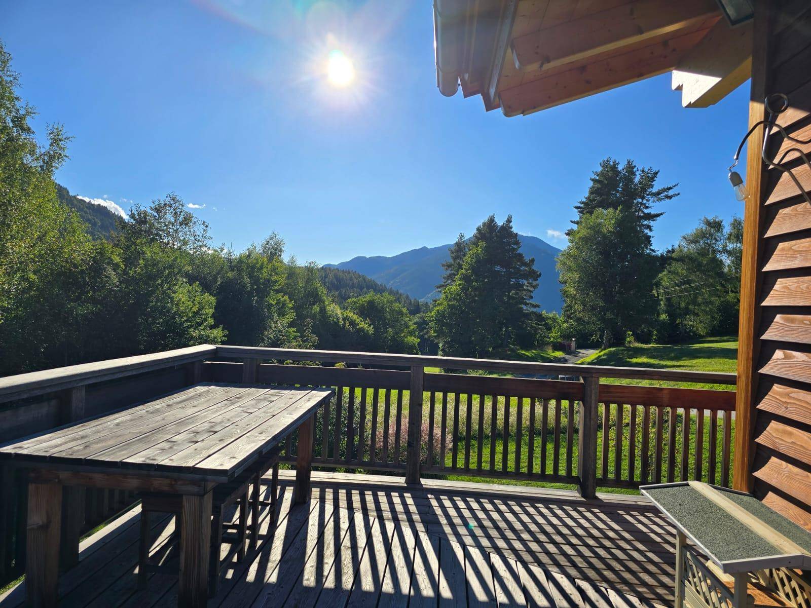 Sonniger Holzbalkon mit Holztisch und Bergblick, ideal für Mahlzeiten im Freien.