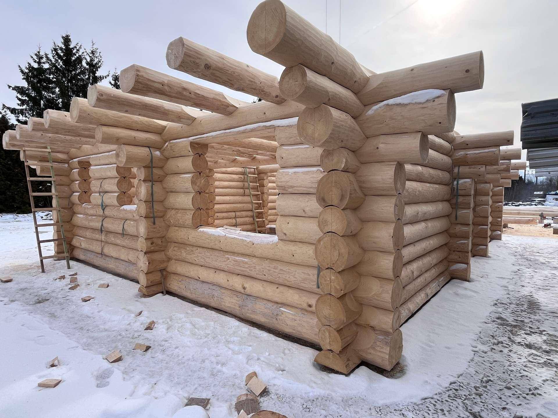 Detailansicht der Holzstammkonstruktion eines im Bau befindlichen Blockhauses im Winter.