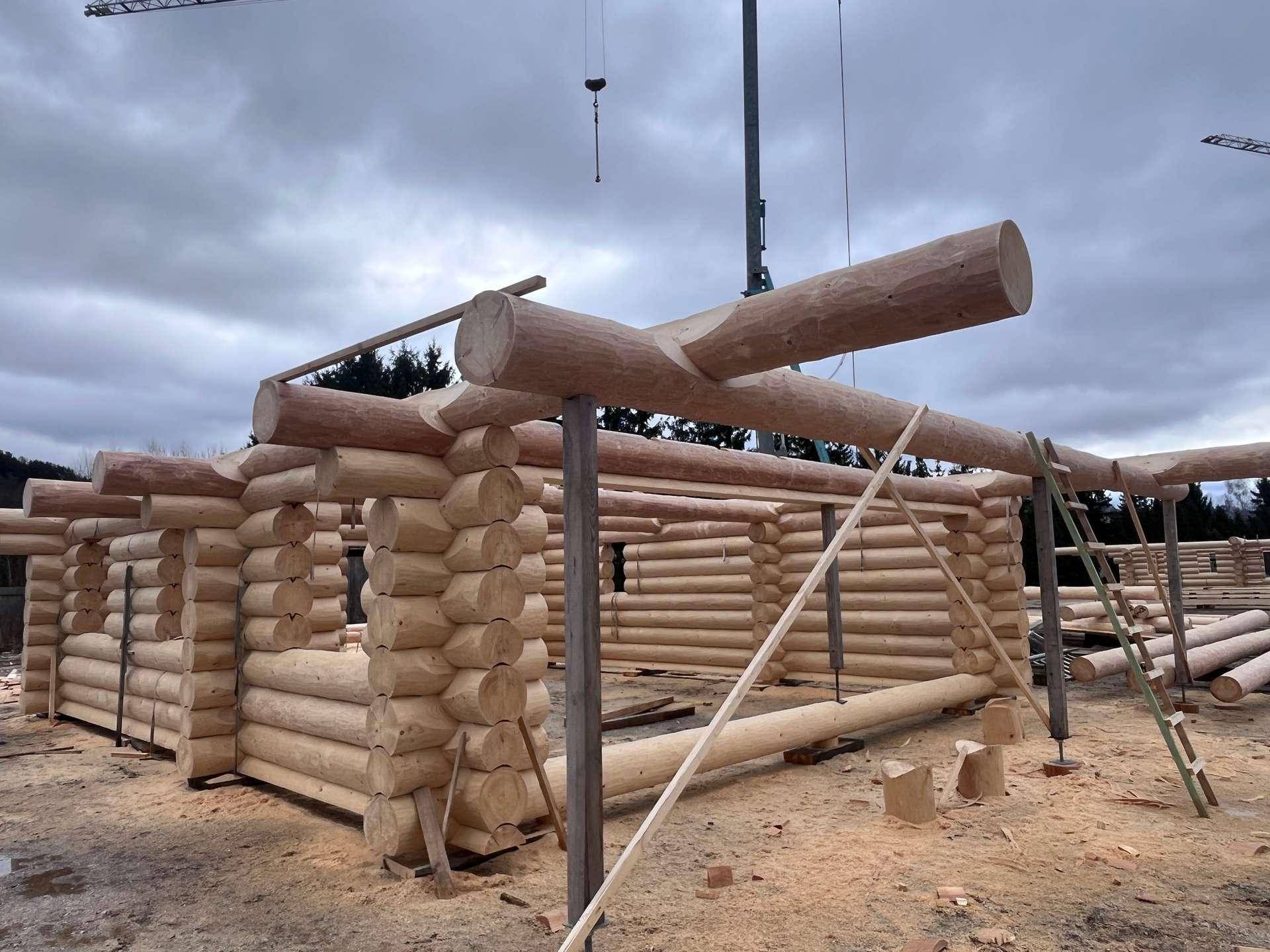 Fortschrittlicher Bau eines Blockhauses mit sichtbaren Holzstämmen und temporären Stützen.
