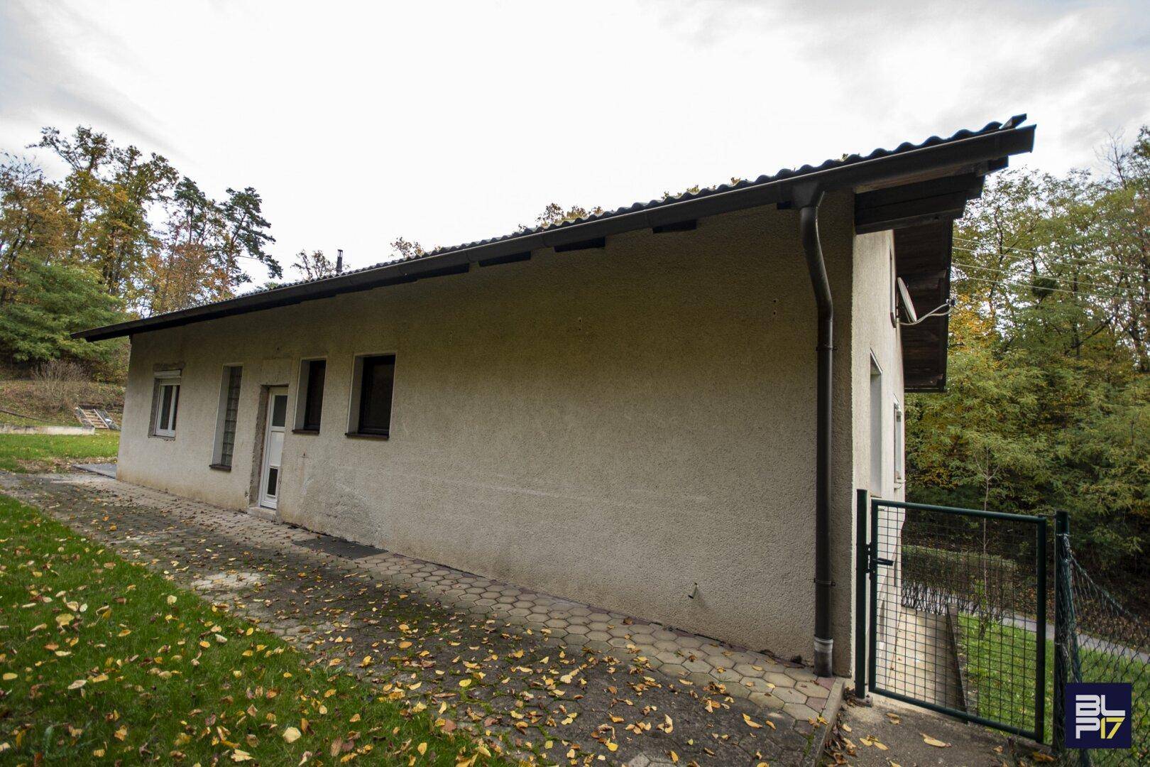 Seitenansicht des Gebäudes mit Zugang zum Gartenbereich und umgebender Natur.