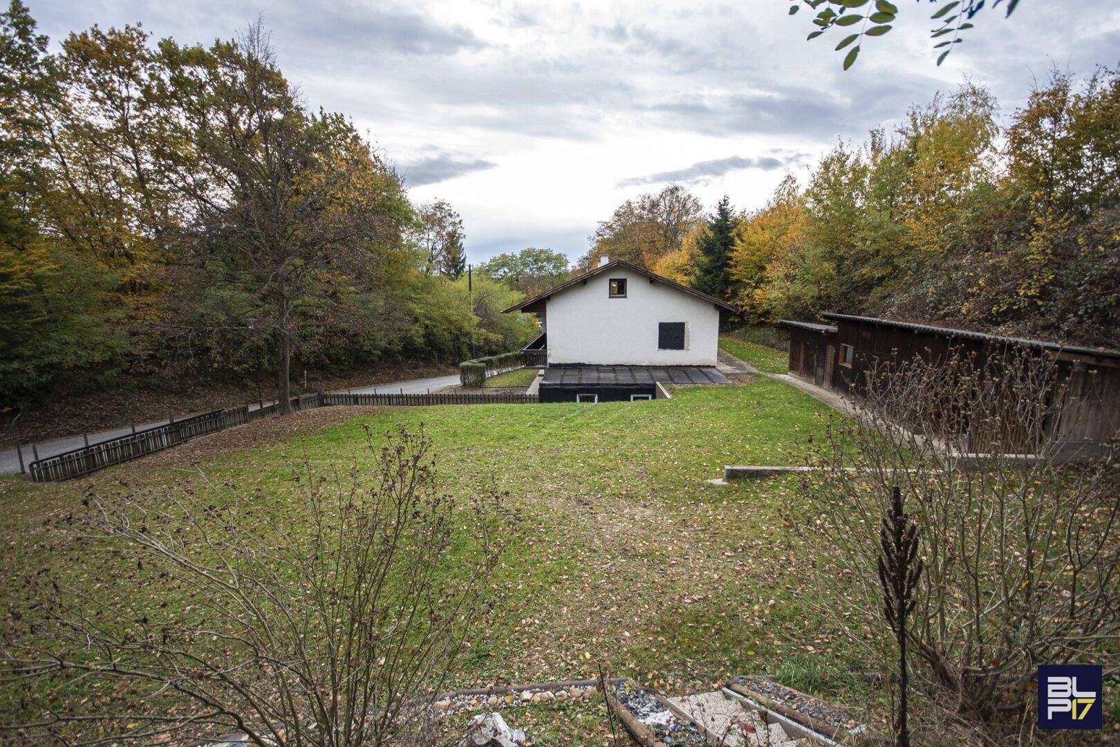 Weitläufige Ansicht des Anwesens mit Hauptgebäude, Nebengebäude und großem Garten.