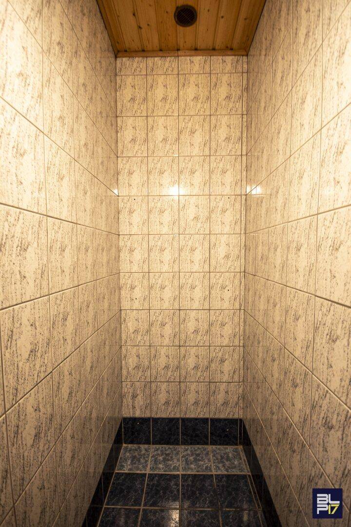 Kleiner Raum mit Fliesenwänden und Holzdecke, möglicherweise eine Sauna oder Dampfbad.