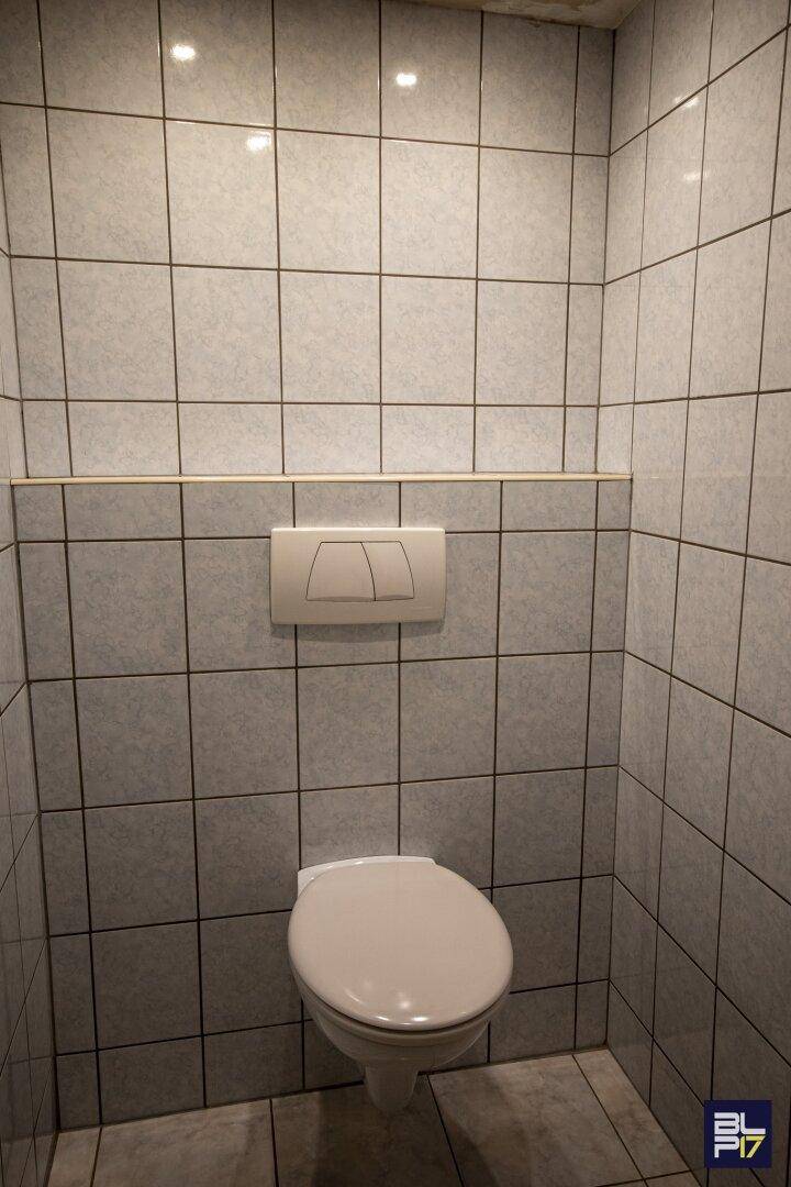 Modern geflieste separate Toilette mit Wand-WC und Spülkasten.