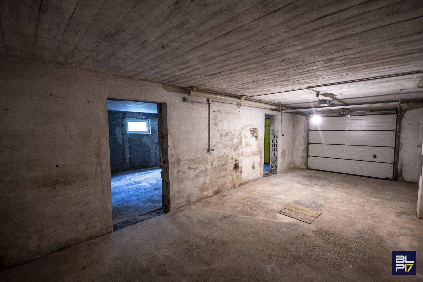 Geräumige Garage im Kellergeschoss mit Rolltor und Zugang zu weiteren Räumen.