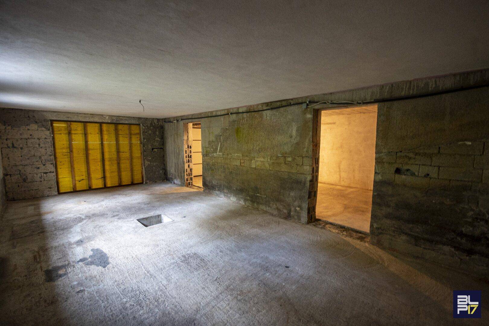 Unfertiger Kellerraum mit Betonboden und unverputzten Wänden, bereit für den Ausbau.