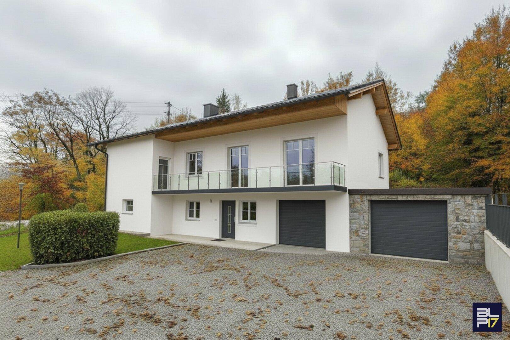 Modernisiertes Haus mit Balkon und Garage, umgeben von herbstlicher Natur.