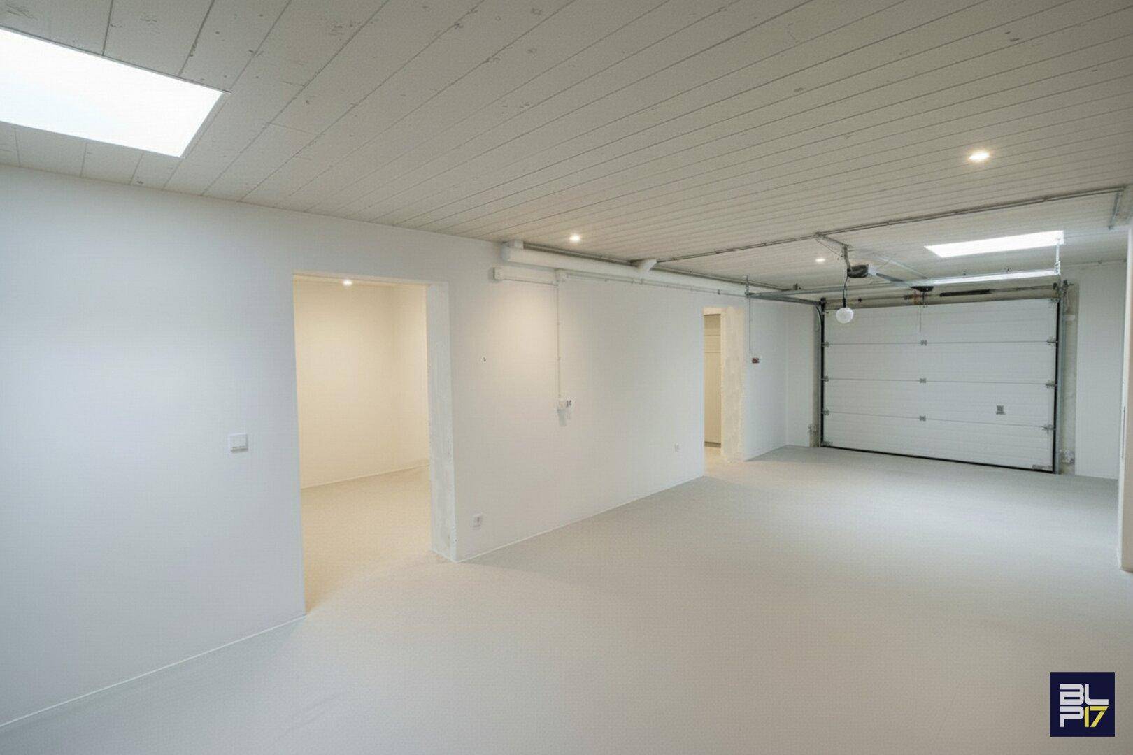 Renovierte Garage mit weiß gestrichenen Wänden, hellem Boden und Deckenverkleidung.