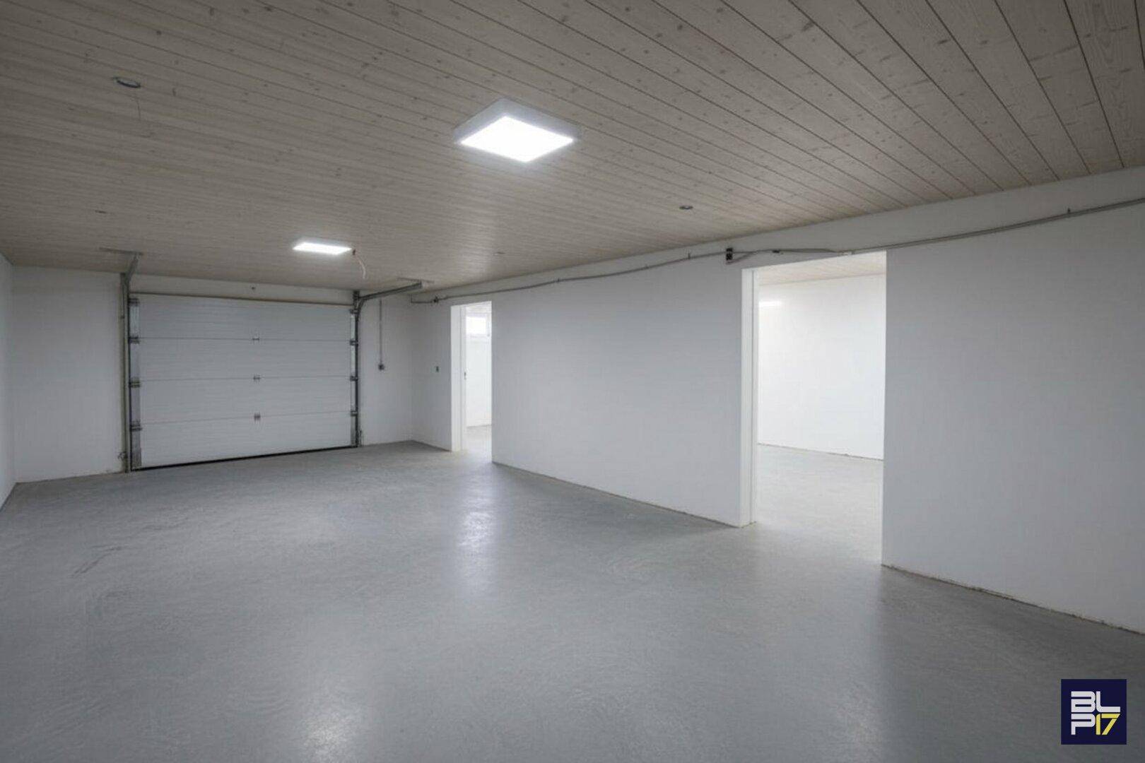 Renovierte Garage mit weiß gestrichenen Wänden, hellem Boden und Deckenverkleidung.