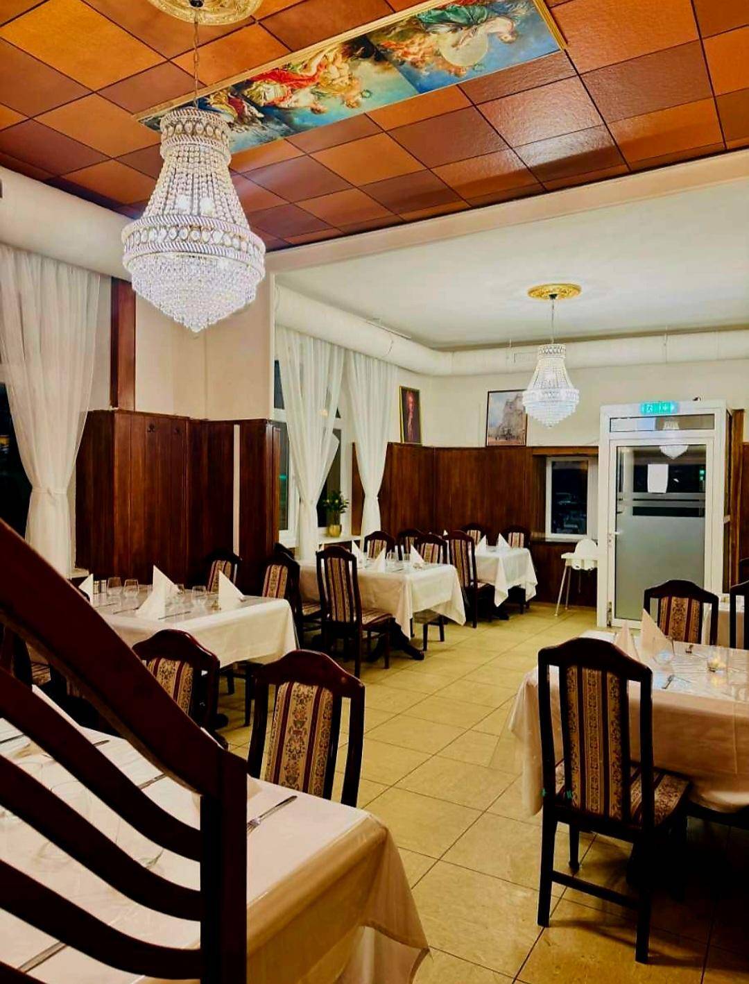 Einladender Speisesaal mit eleganten Kronleuchtern, Holzvertäfelung und kunstvollen Deckenmalereien, ideal für festliche Anlässe.