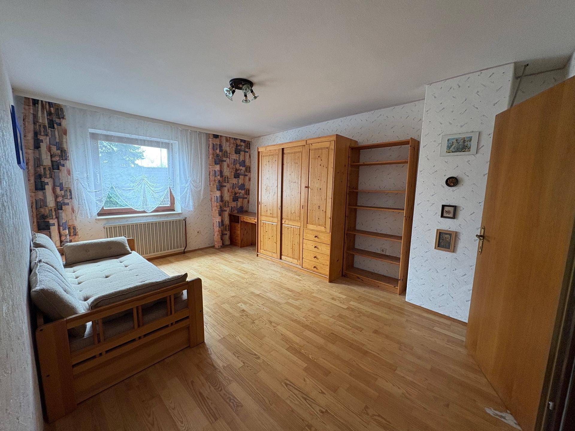 Schlafzimmer mit Holzbett, Kleiderschrank und Parkettboden.