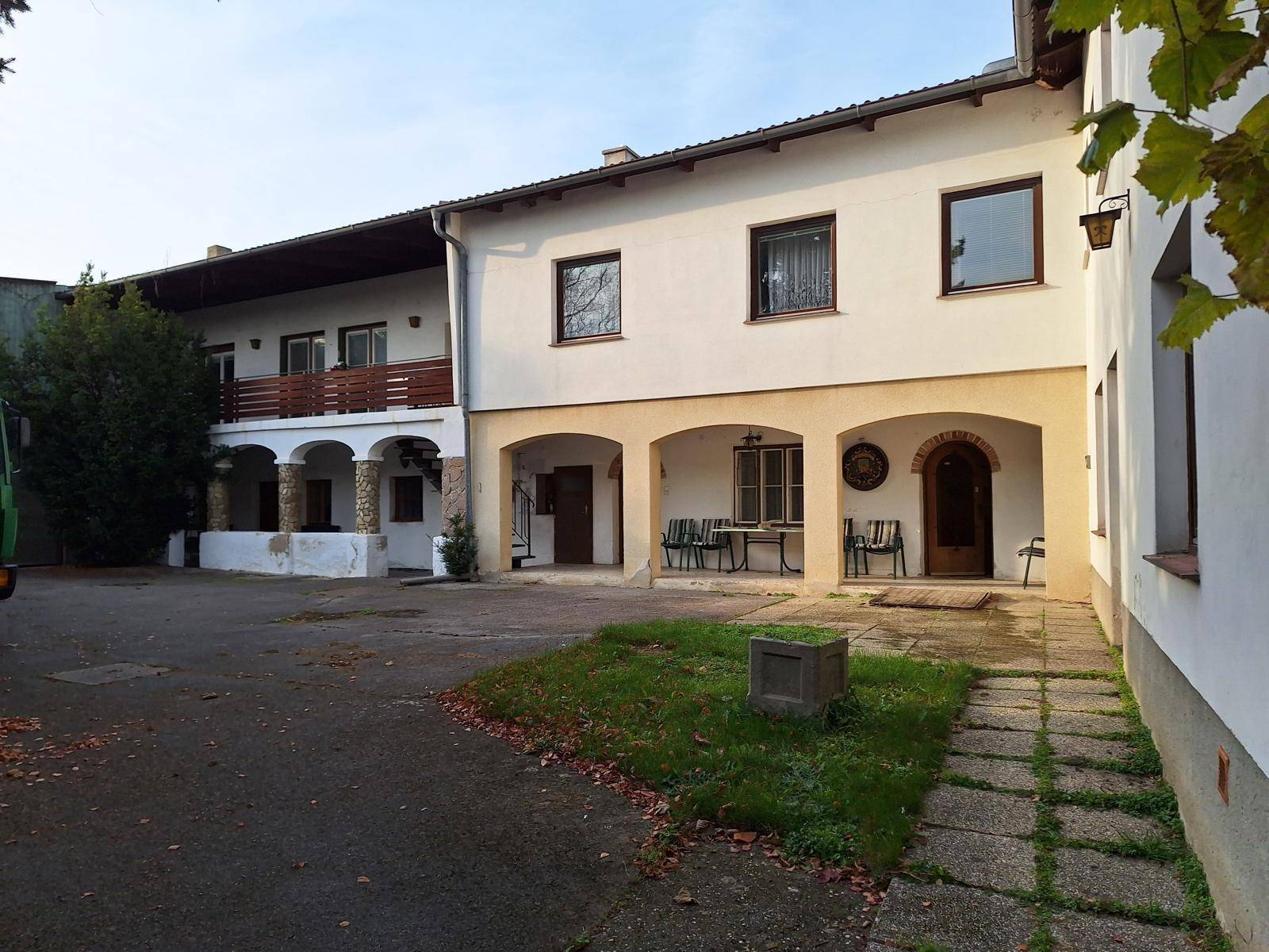 Hinterhof mit gepflastertem Bereich, überdachter Terrasse und Sitzgelegenheiten.