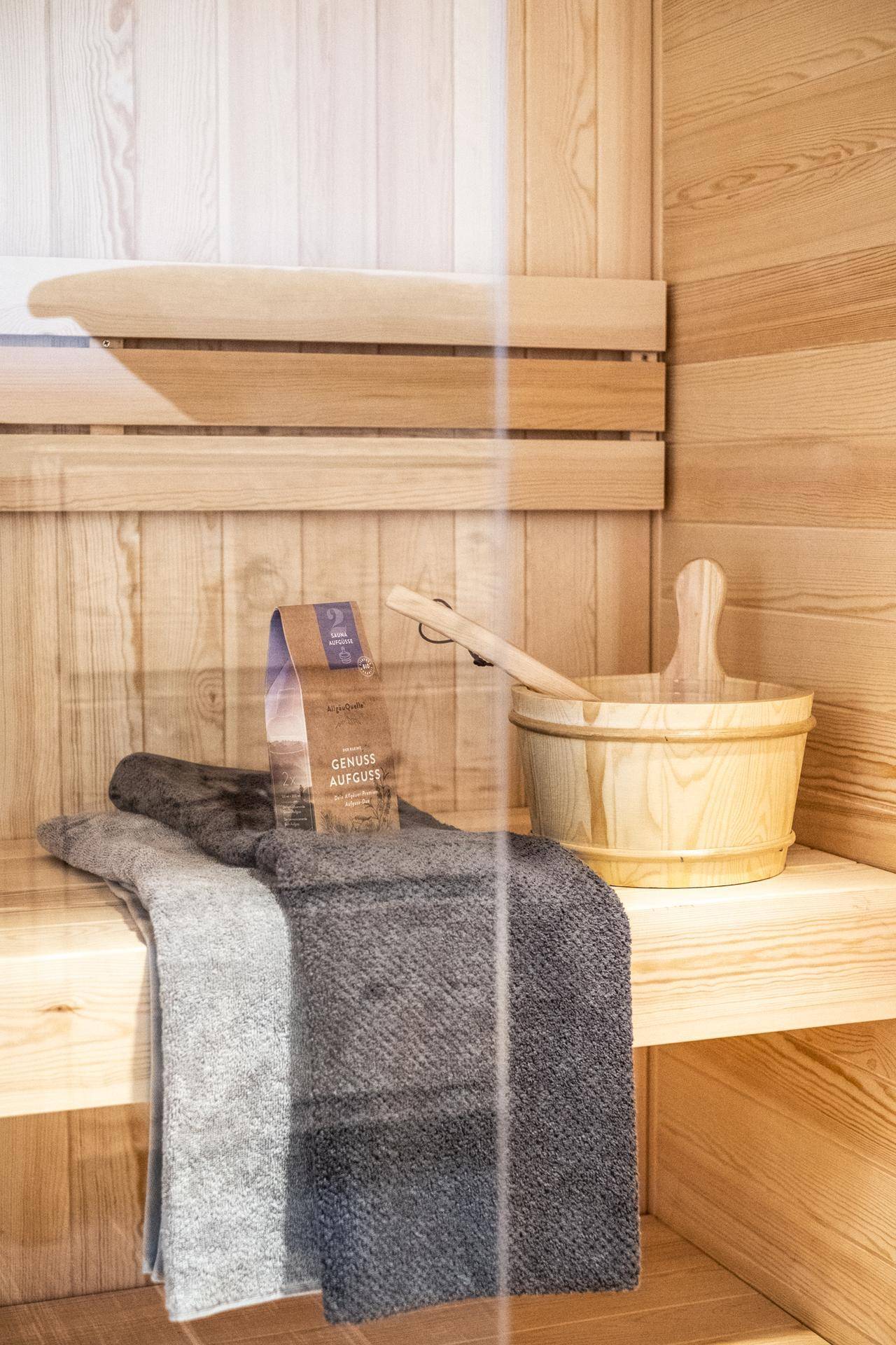 Moderne Sauna mit Holzbänken, Eimer und Handtüchern für Entspannung.