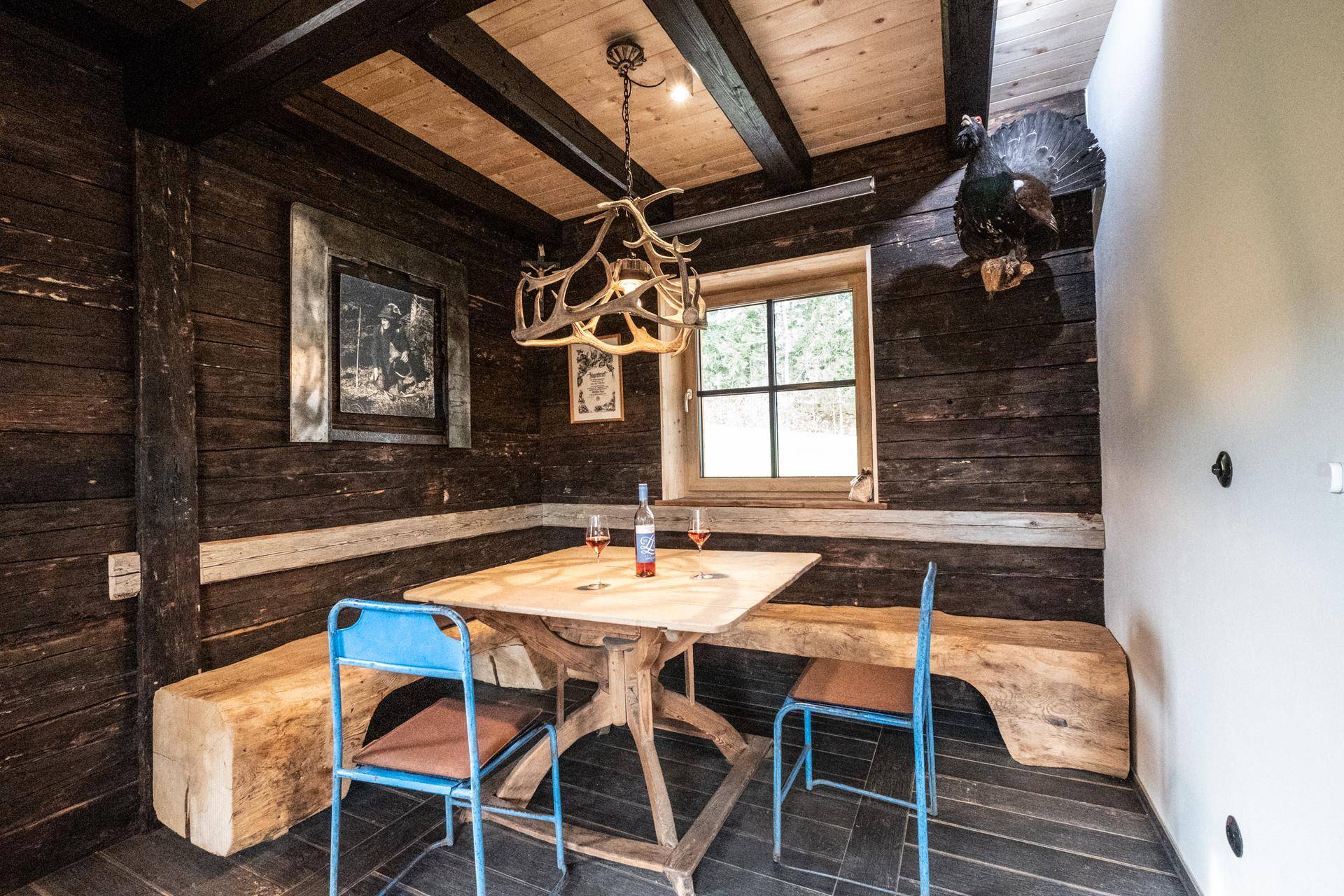 Gemütlicher Essbereich mit Holztisch, Bänken und Hirschgeweih-Lampe.