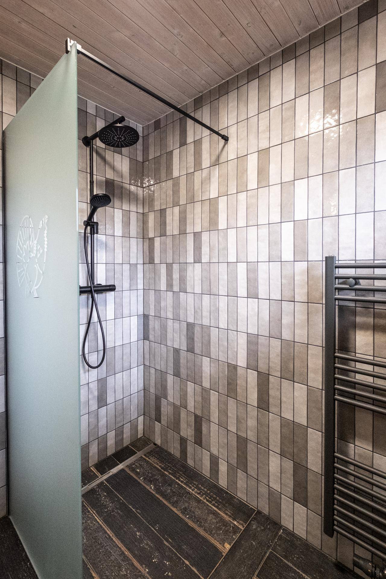 Duschbereich mit modernen Fliesen, Regendusche und beheiztem Handtuchhalter.