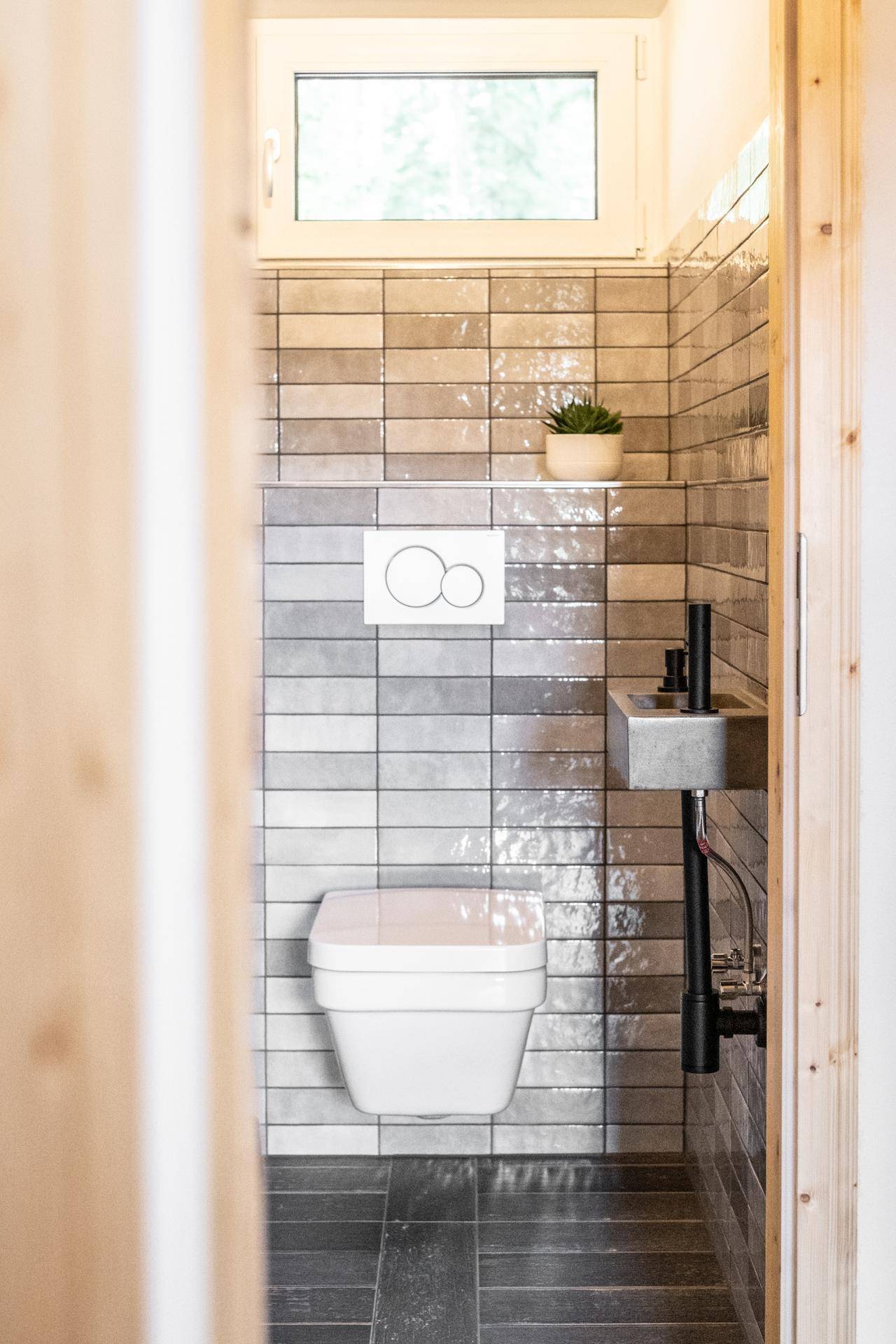 Separate Gästetoilette mit Wand-WC, kleinem Waschbecken und Fenster.