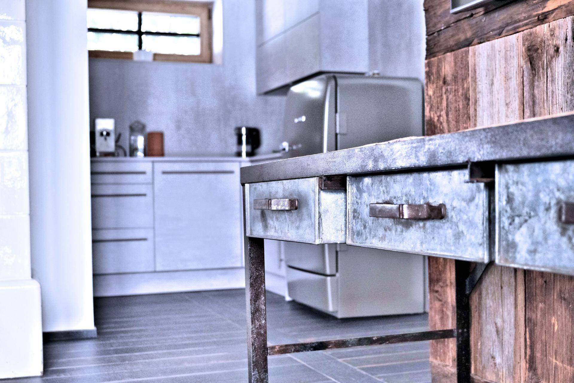 Moderne Küche mit rustikalem Beistelltisch und Blick auf die Holzwand.