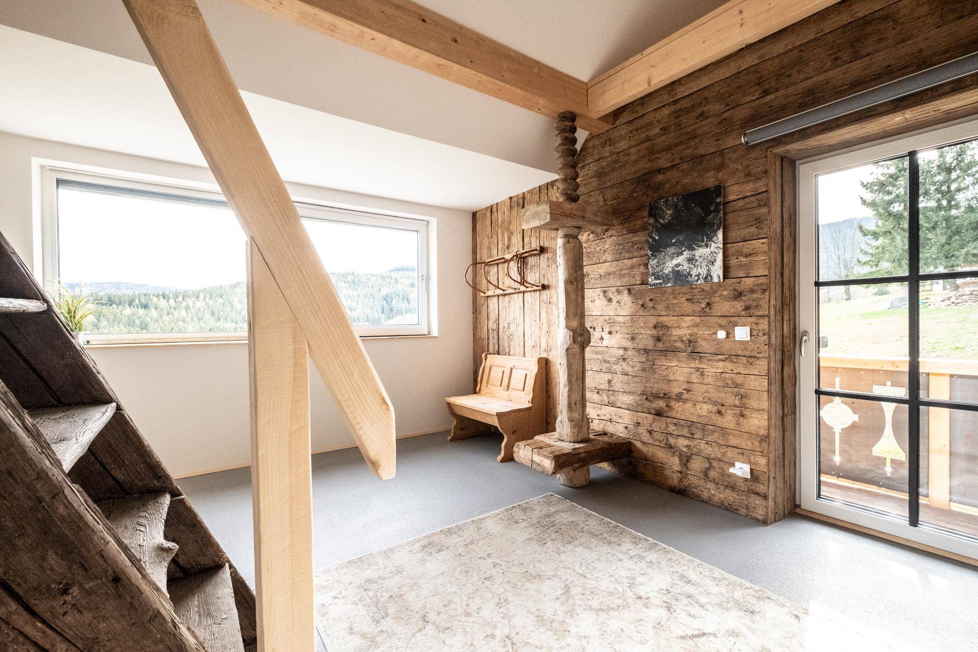 Heller Flurbereich im Obergeschoss mit Holzwänden, Sitzbank und weitem Ausblick.