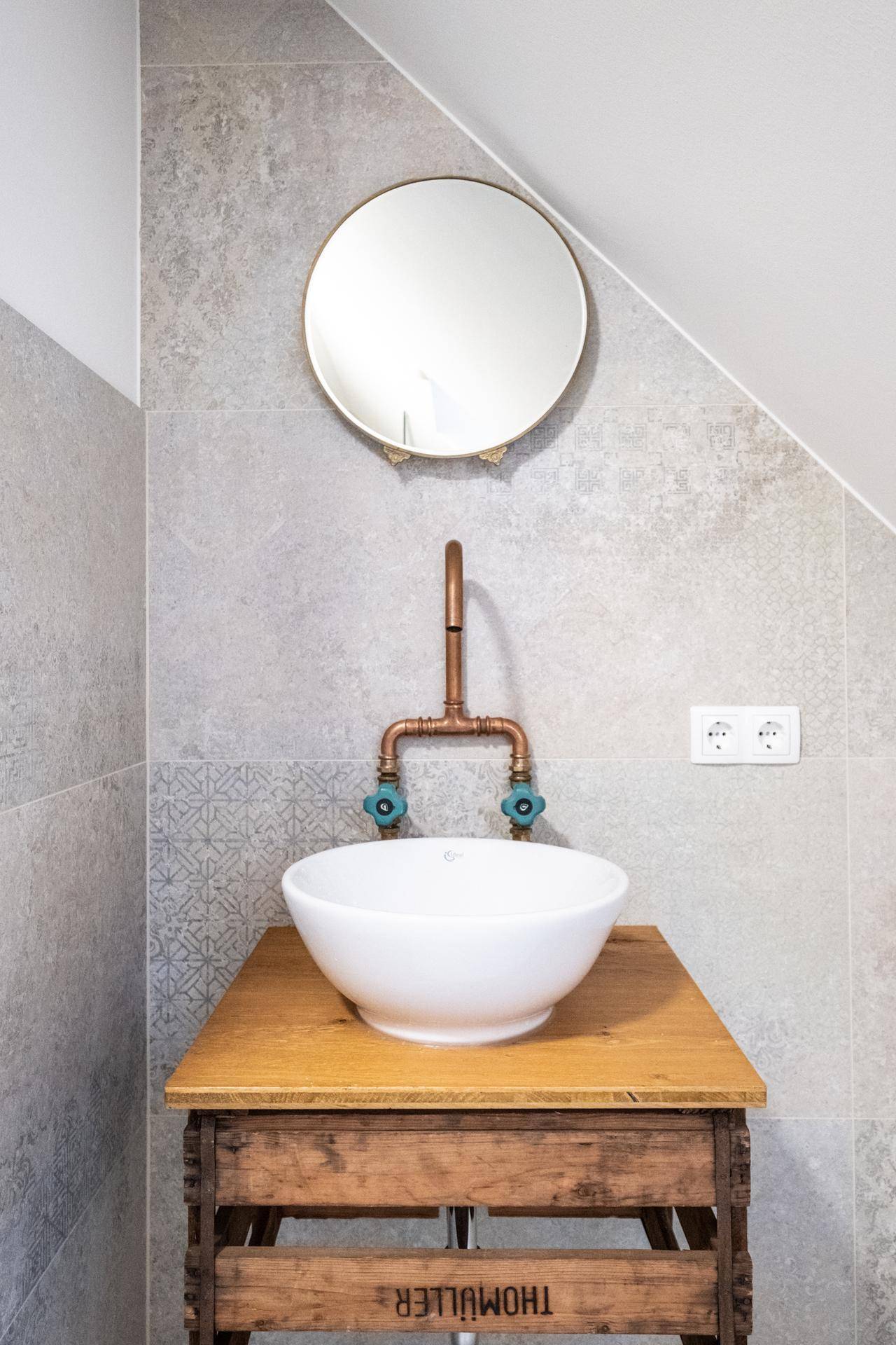 Modernes Badezimmer im Dachgeschoss mit Waschtisch, Spiegel und schrägen Wänden.