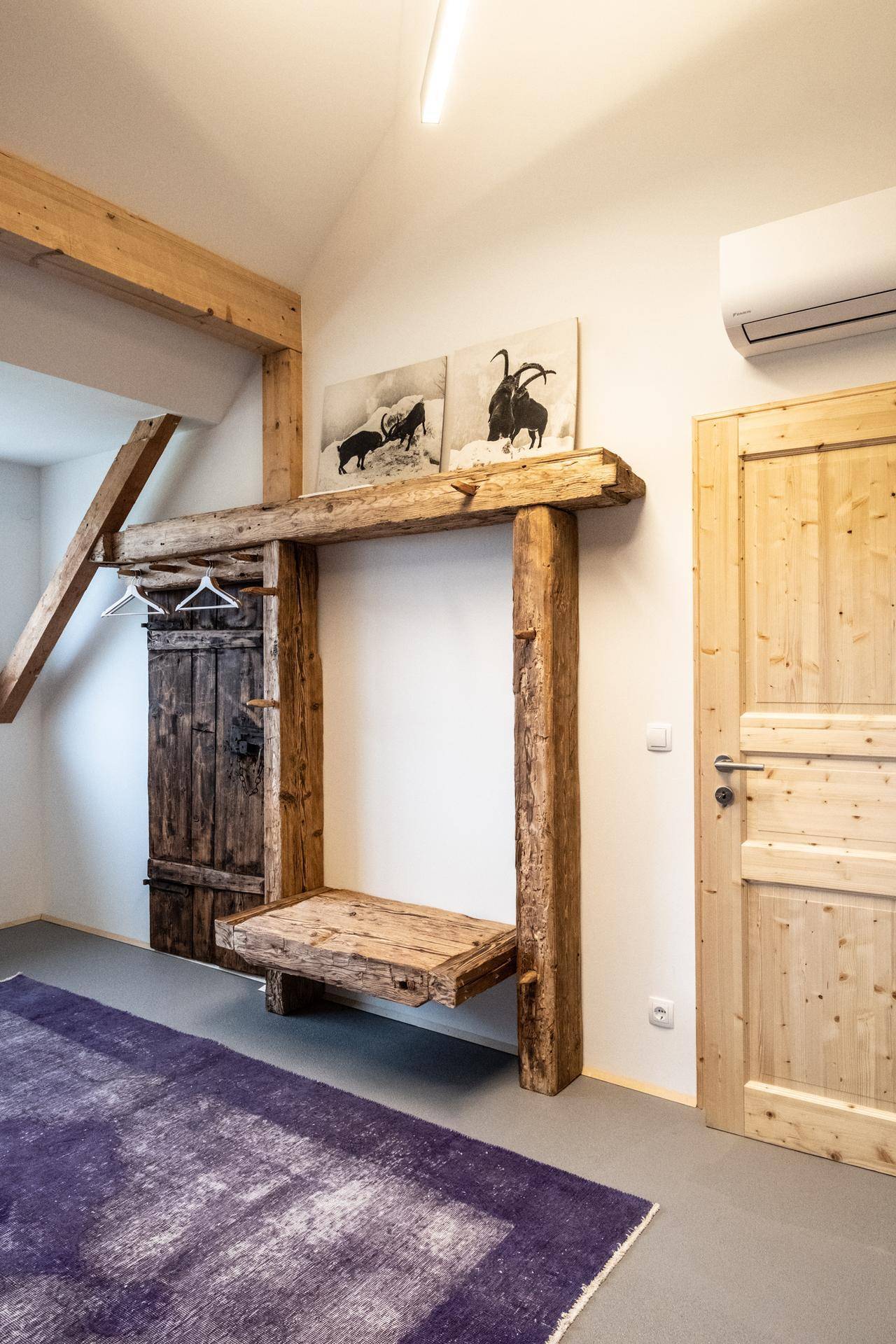 Schlafzimmer mit rustikalem Holzregal, Holztüren und lila Teppich.