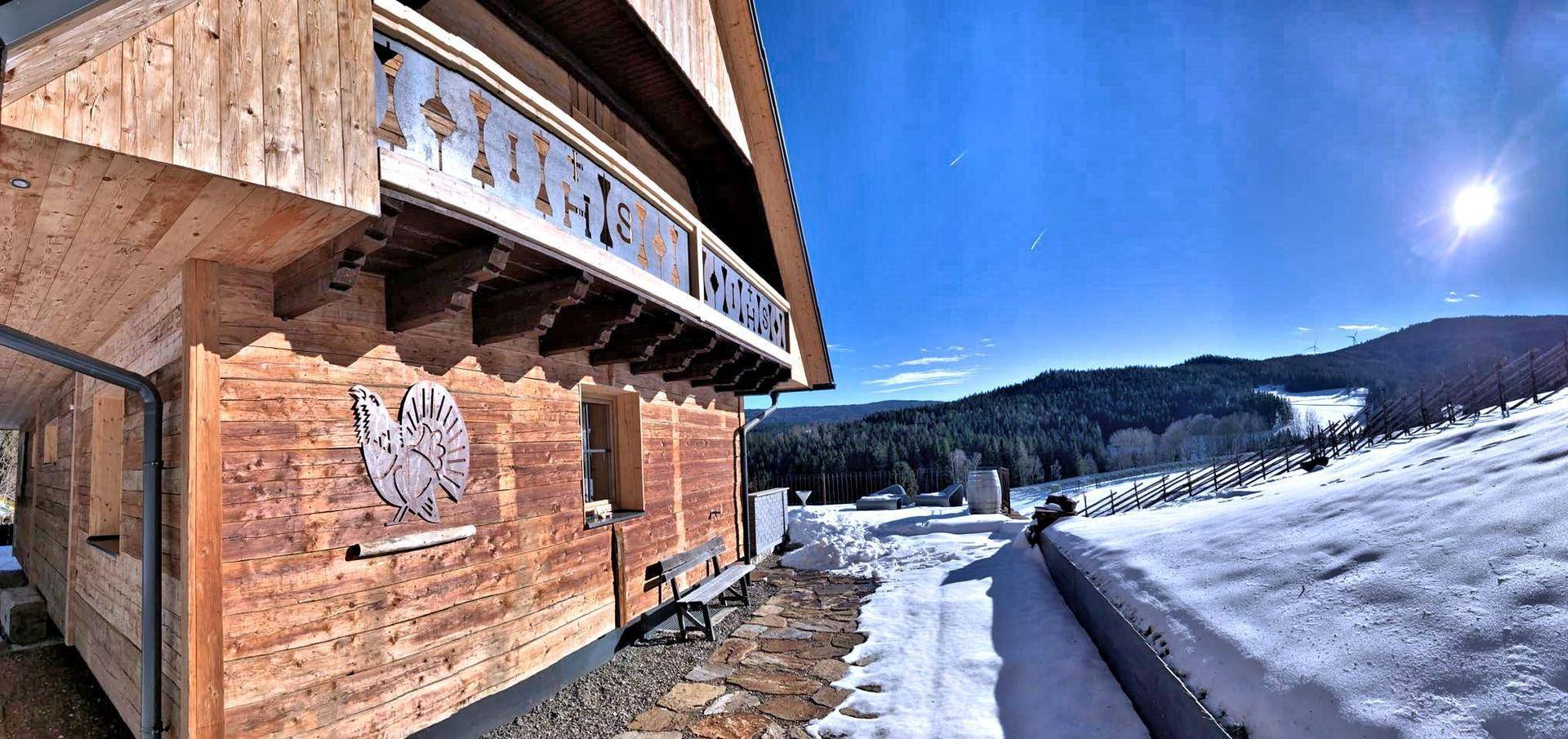 Winterliches Holzchalet mit weitem Blick auf die verschneite Landschaft und Skipisten.