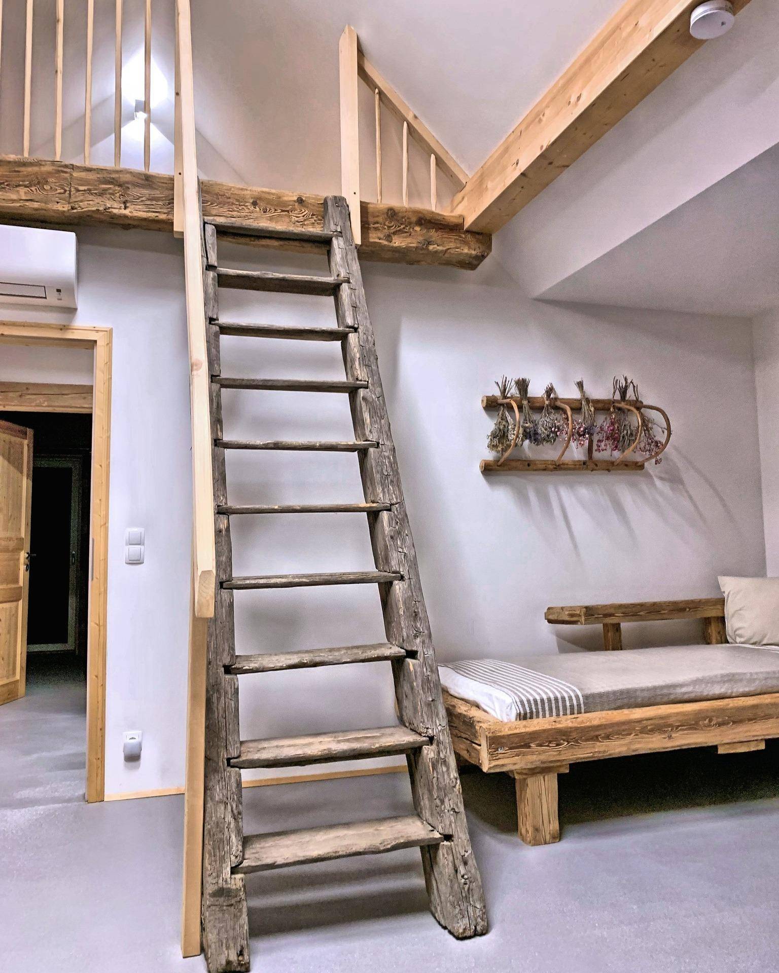 Schlafbereich mit Holzleiter zum Loft und rustikalem Holzbett.