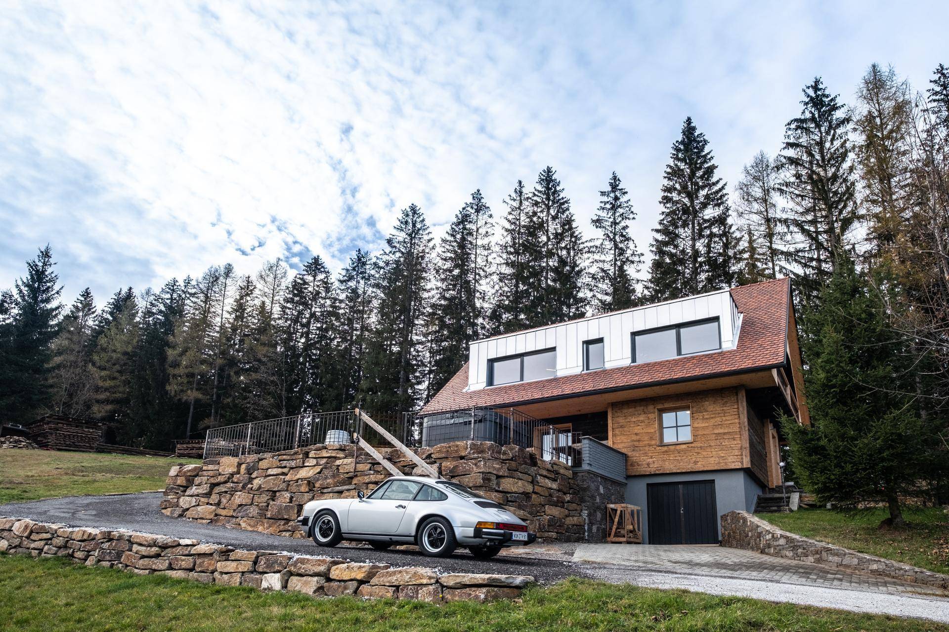 Charmantes Holzchalet in idyllischer Hügellandschaft mit Zufahrt und Auto.