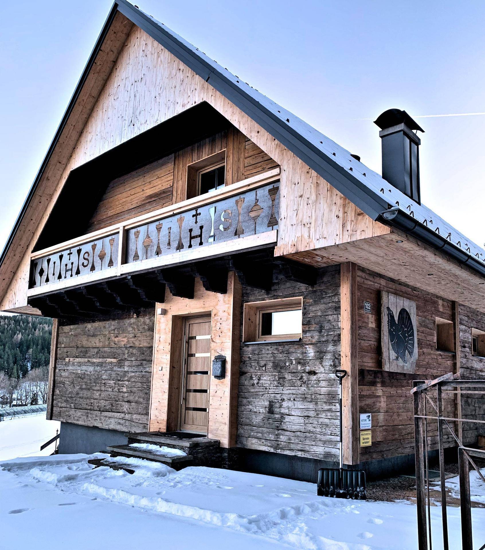 Traditionelles Holzchalet im Winter mit verschneiter Umgebung und klarem Himmel.