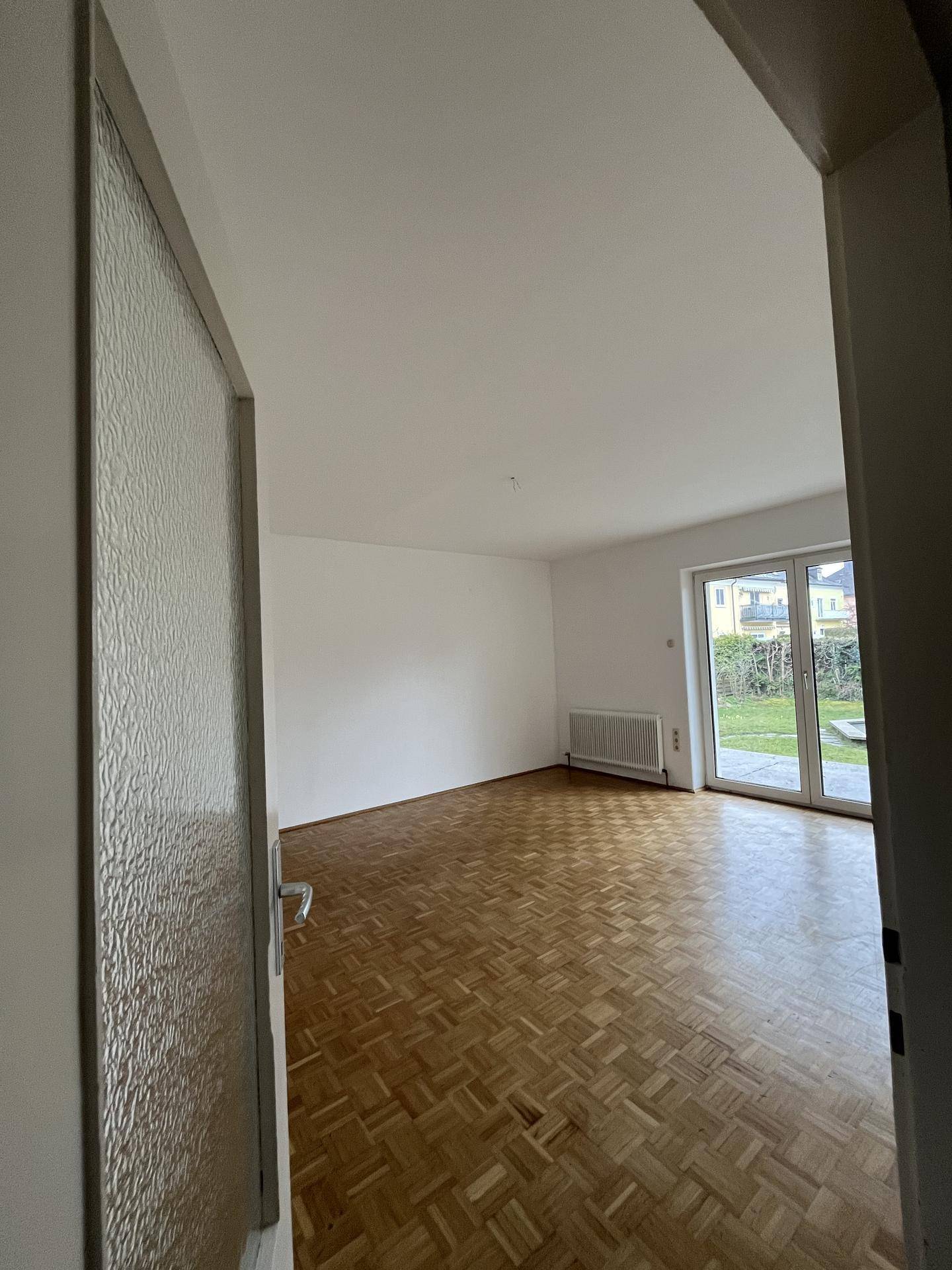 Helles Wohnzimmer mit Parkettboden und direktem Zugang zum Garten.