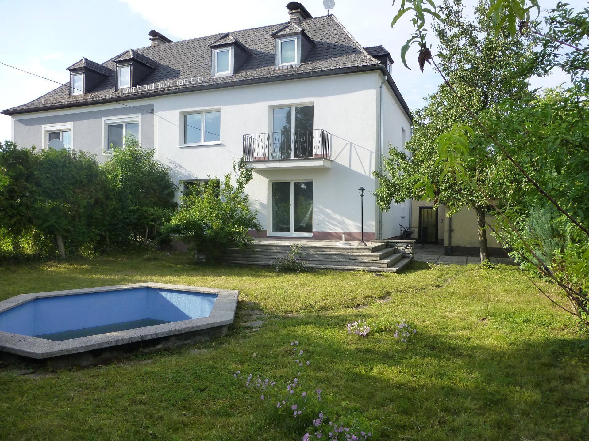 Großzügiger Gartenbereich mit kleinem Pool und Blick auf die Hausfassade.