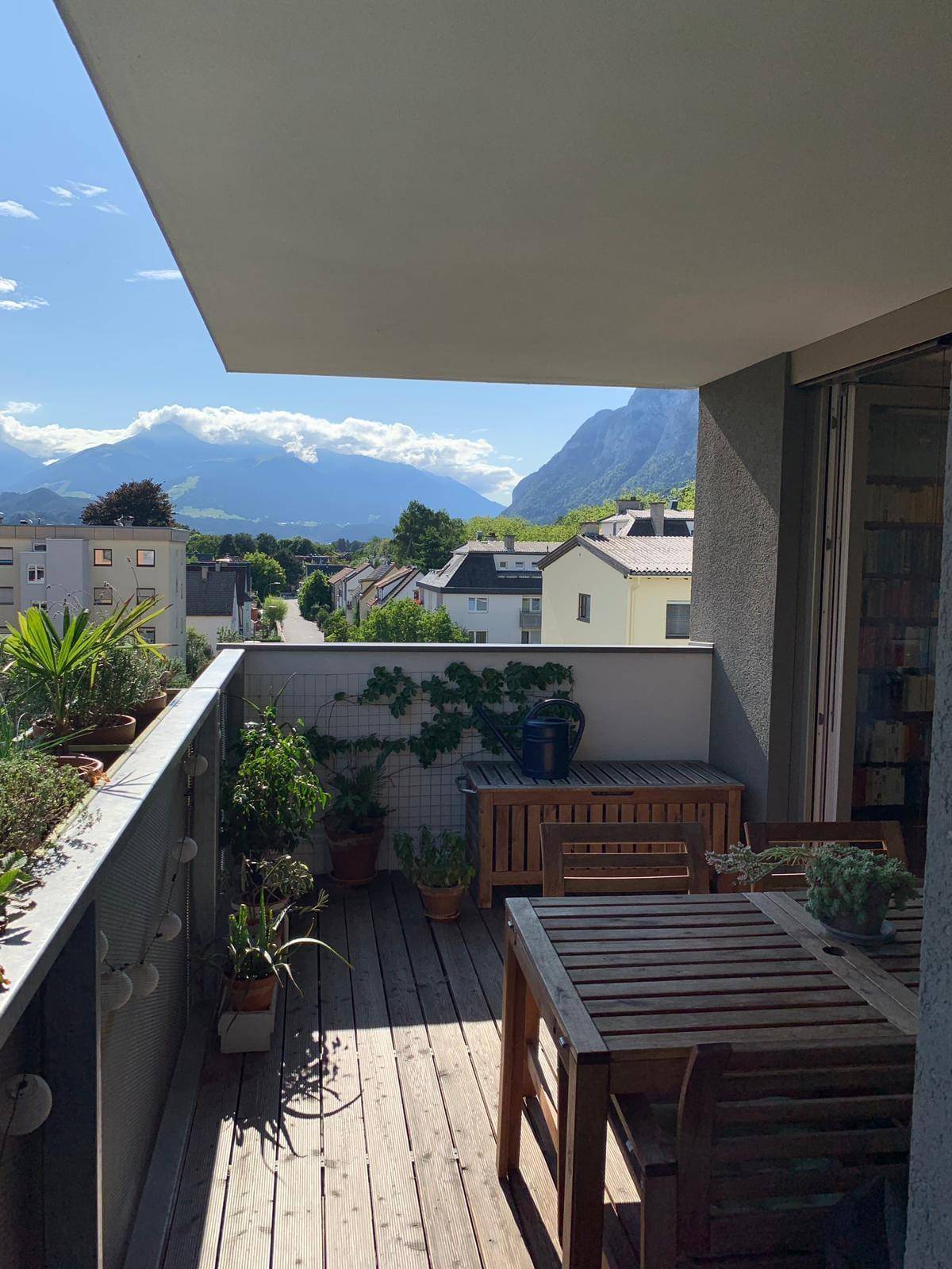 Geräumiger Balkon mit Holzdeck, Gartenmöbeln und Panoramablick auf die Berge.