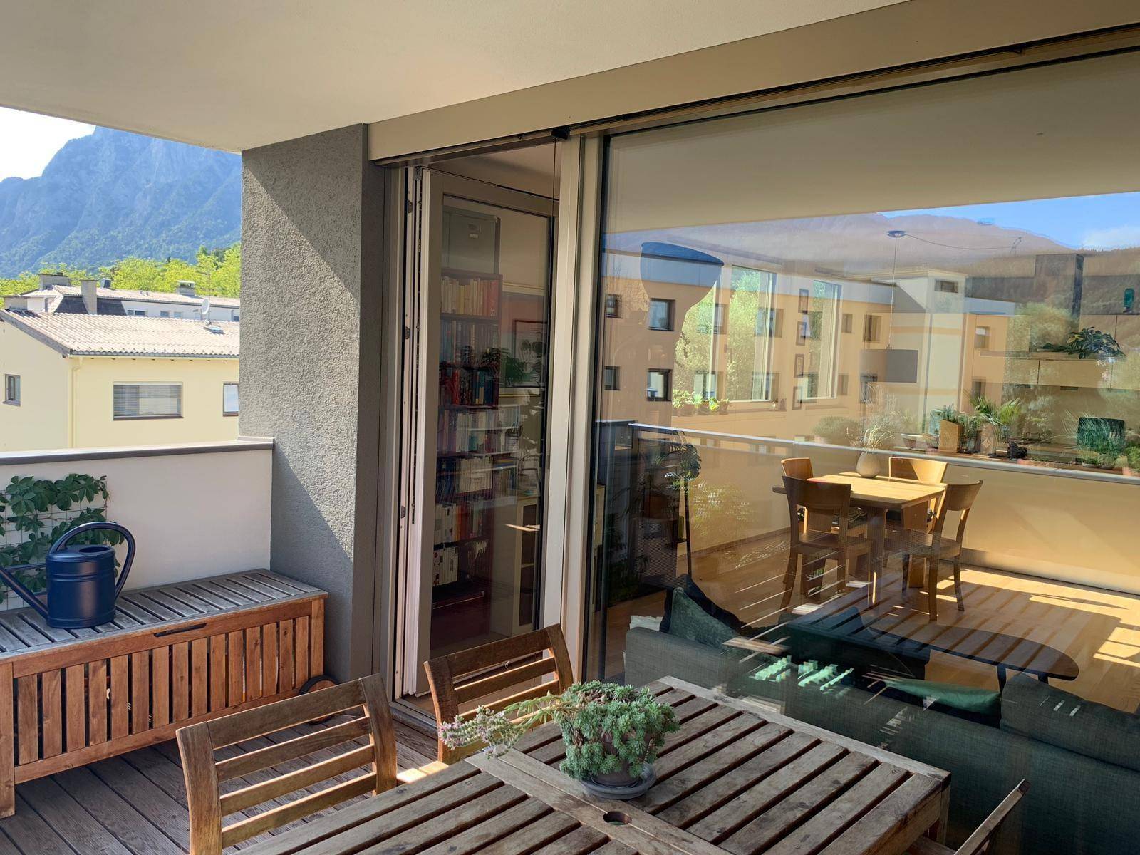 Sonniger Balkon mit Holzmöbeln und weitem Blick auf die umliegende Landschaft.